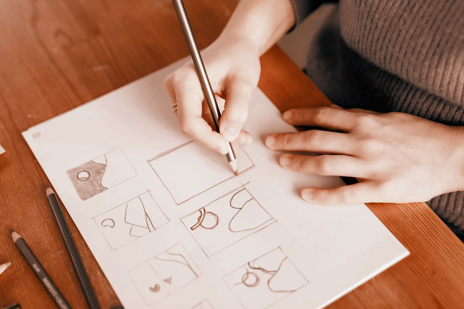 A designer sketching at a wooden table