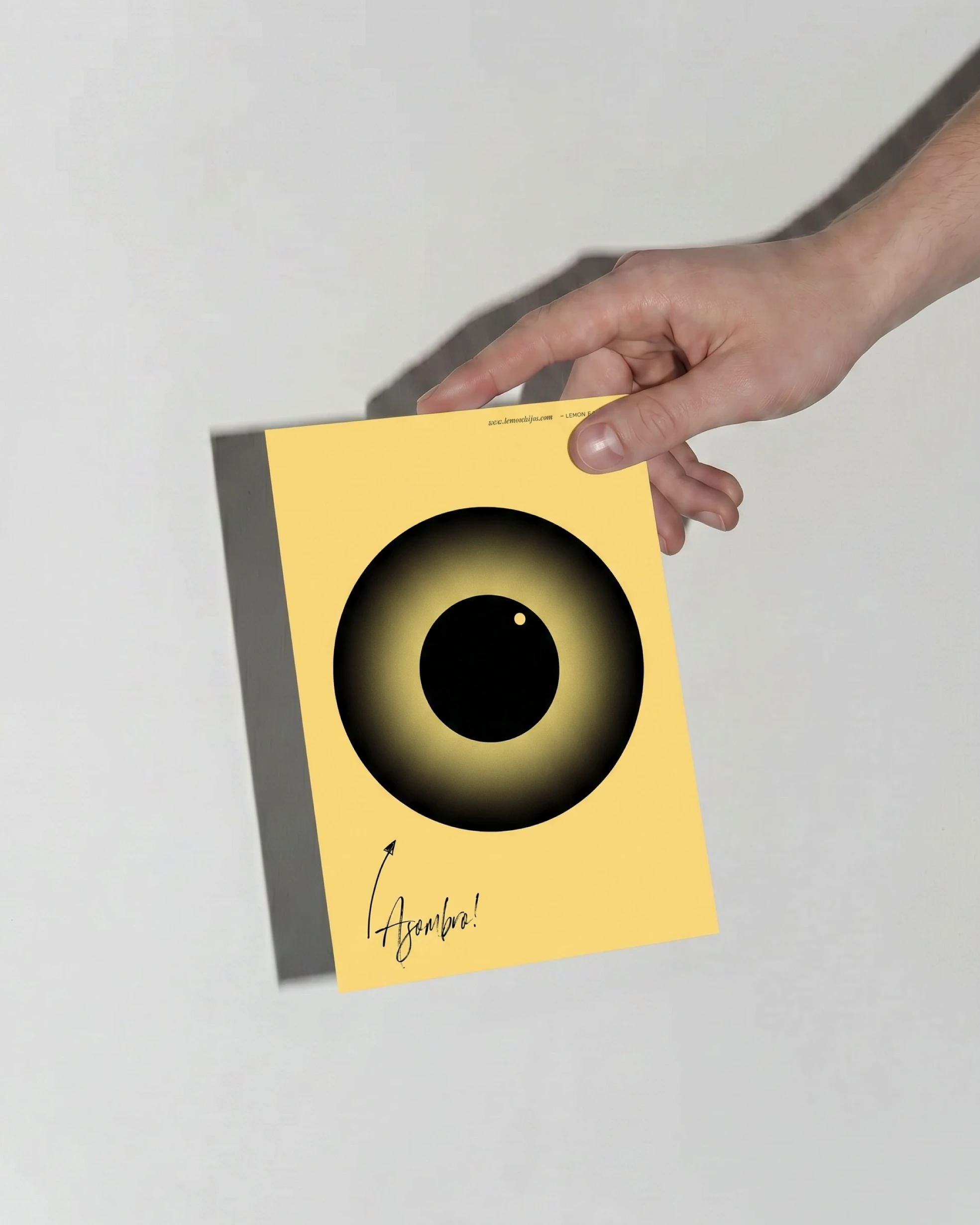 Hand holding a yellow Lemon & Hijos notebook with the eye, brand and illustration design by Sebastian Saavedra