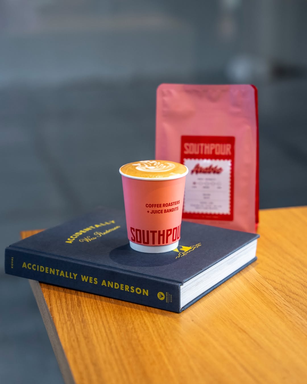 A cup of hot Southpour coffee, in its classic salmon pink colour cup, placed on top of a book. 