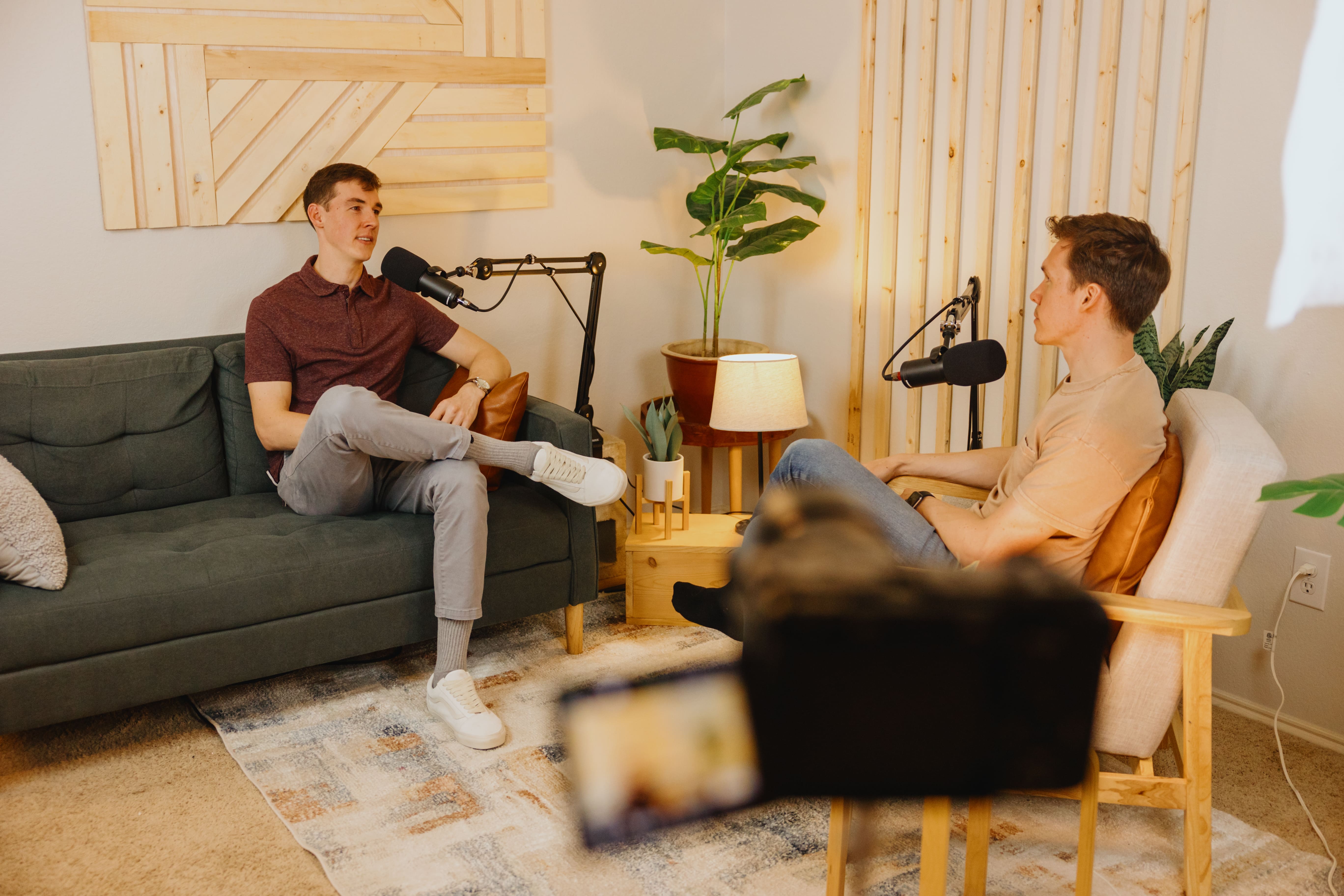 Man wearing baseball hat and beige hoodie sitting on leather couch