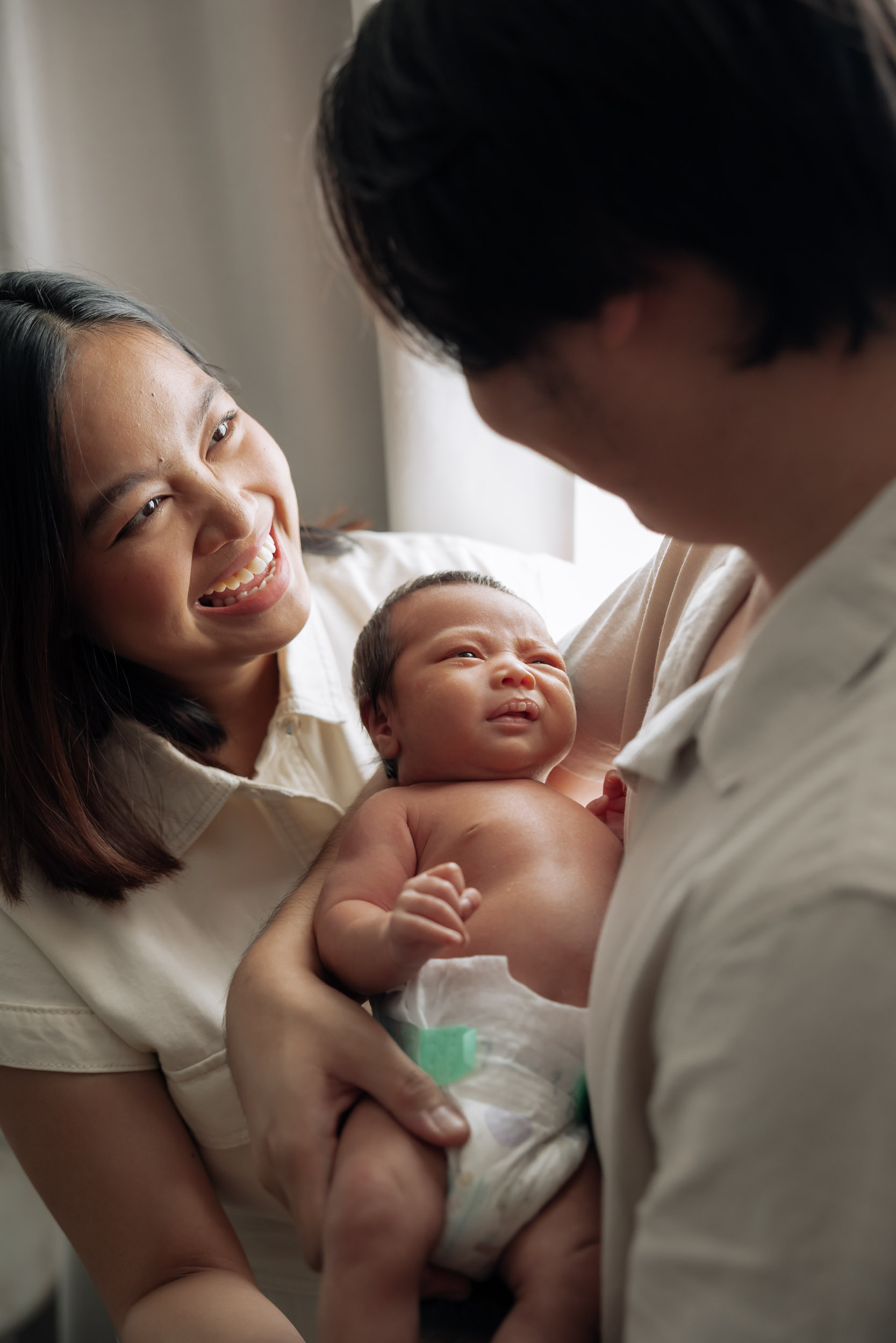 Newborn portrait of family holding baby in soft window light in Mackay