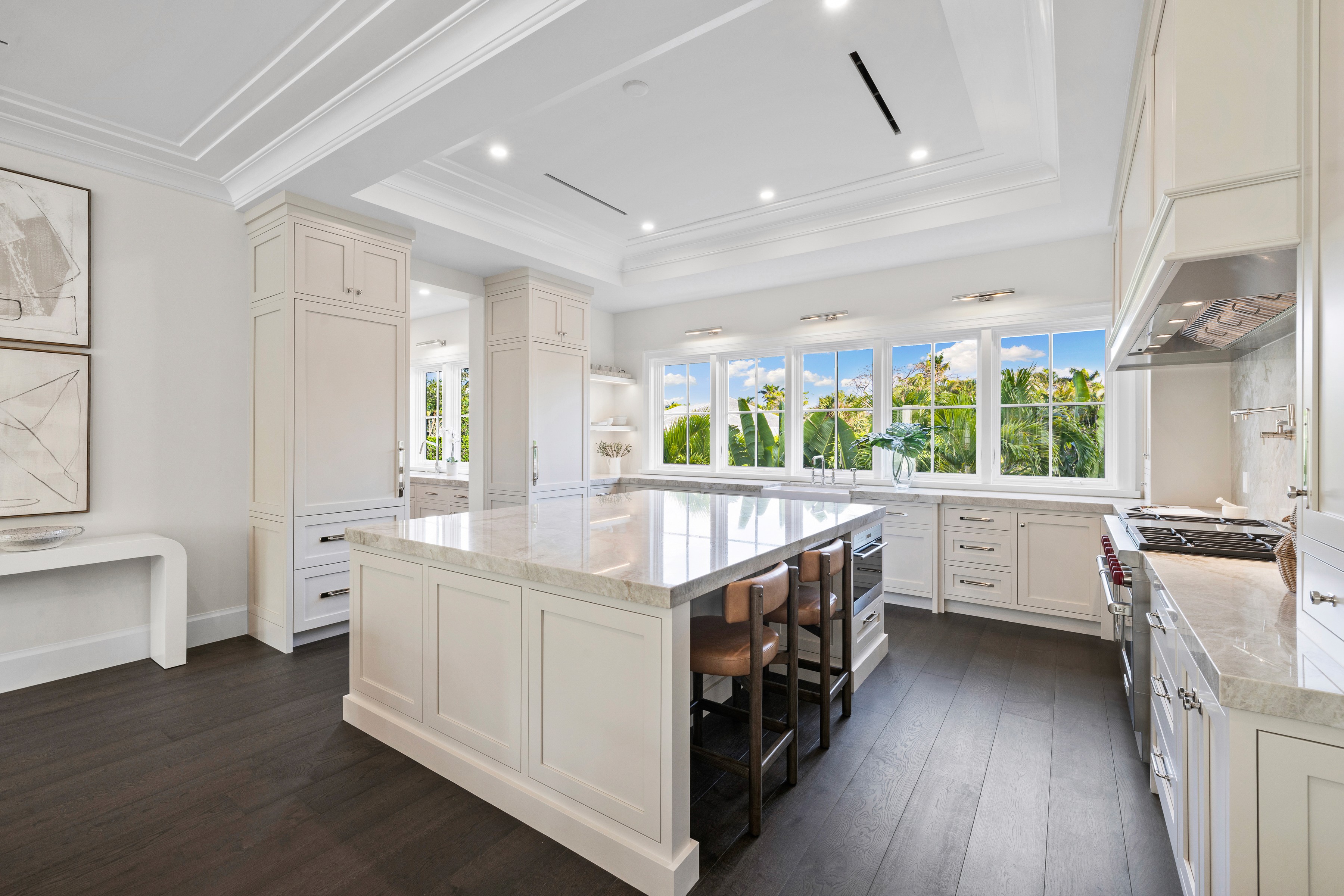 a large kitchen with white counter tops, white cabinets, and a dark wood floor