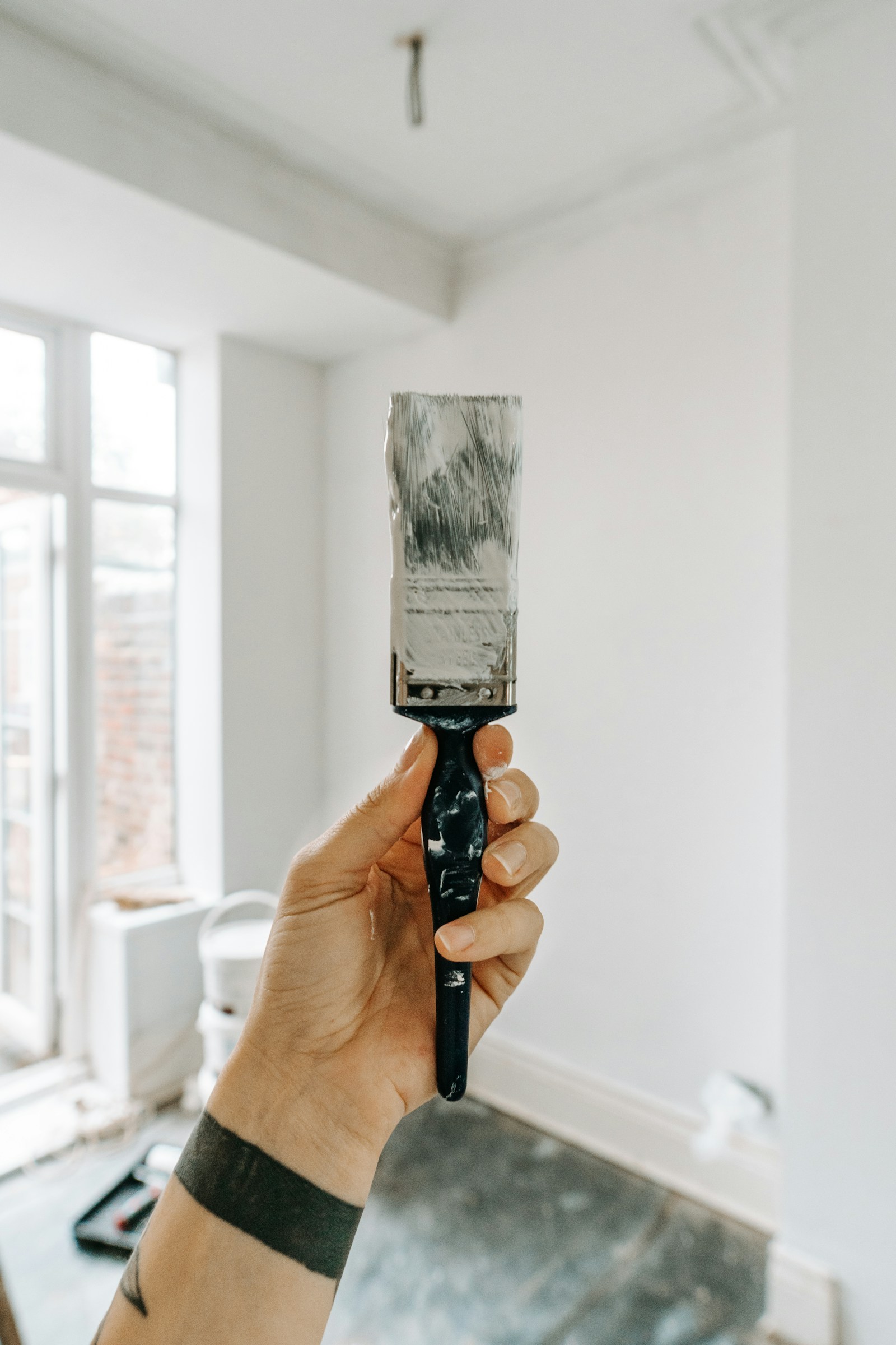 Hand holding a paint brush with white paint
