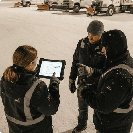 Three people outside in winter looking at a tablet.