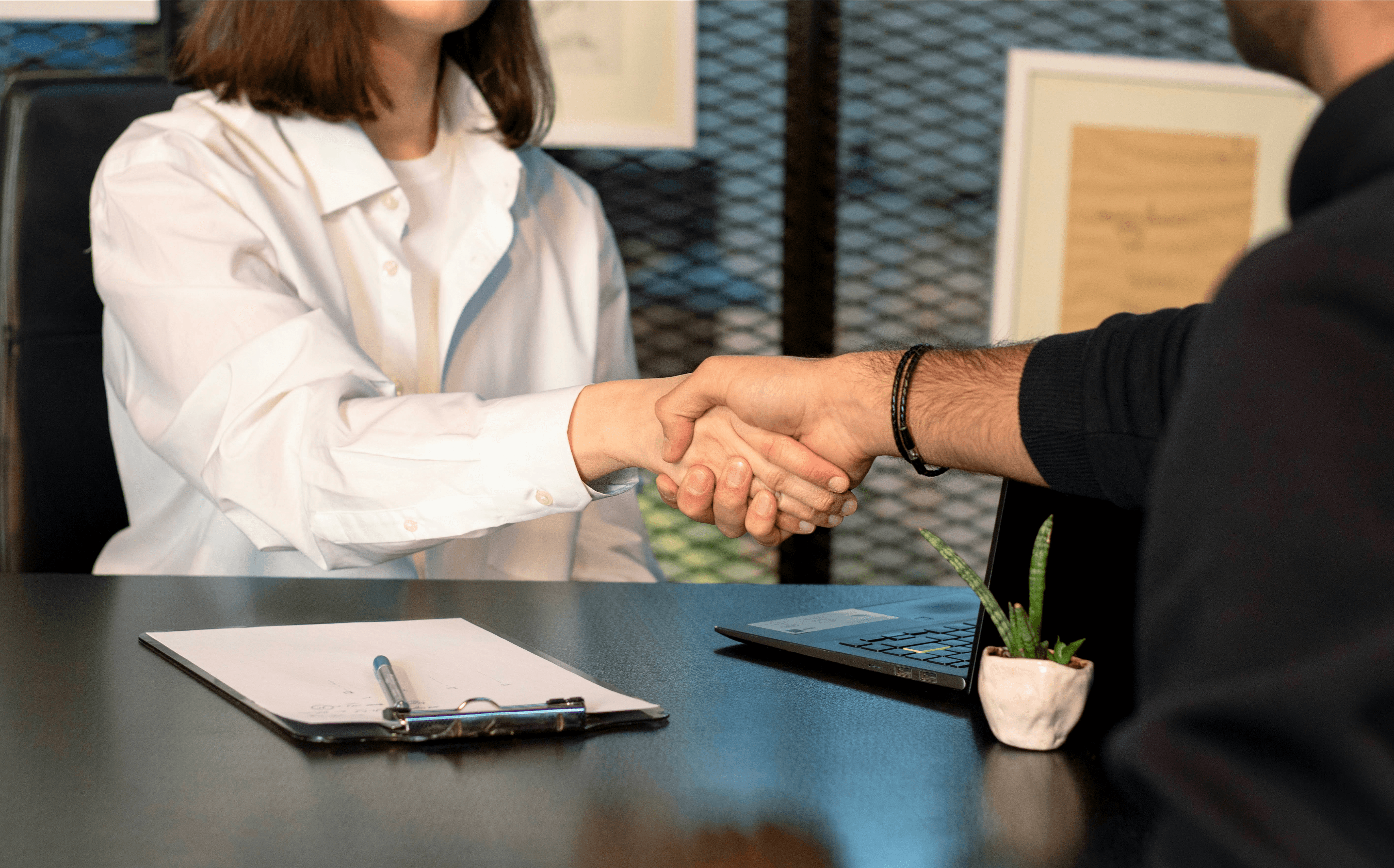 a man and a woman shaking hands in front of a laptop