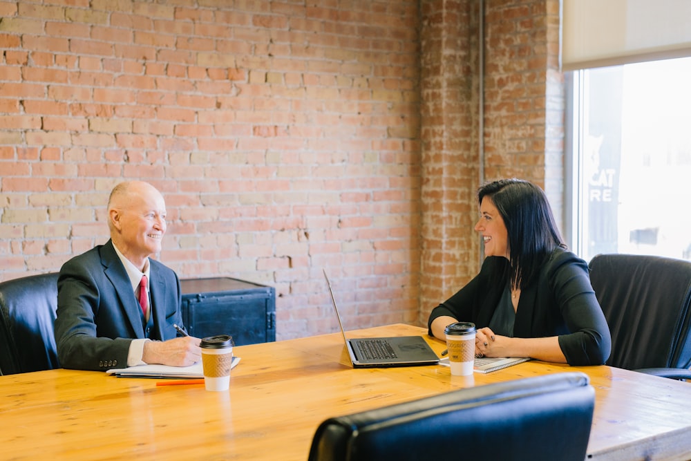 A lady interviewing a man in a boardroom