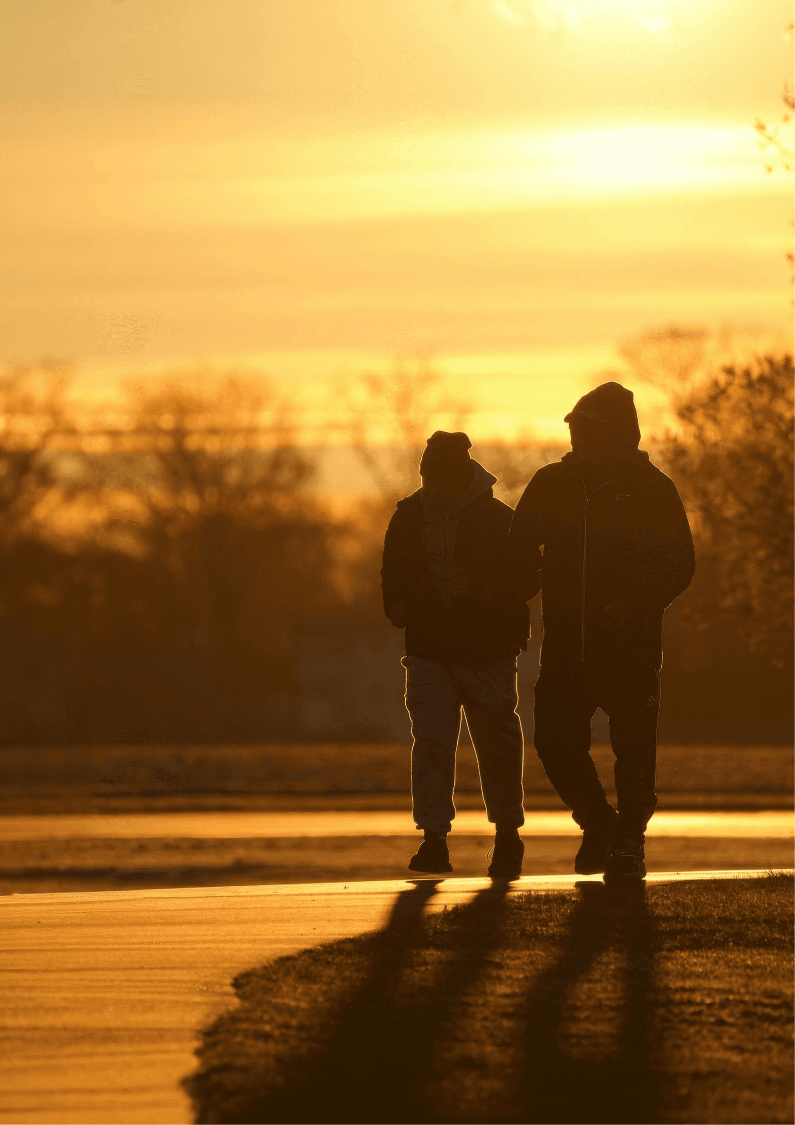 Two businessmen in suits walking down an escalator in a subway station with coffee cups.