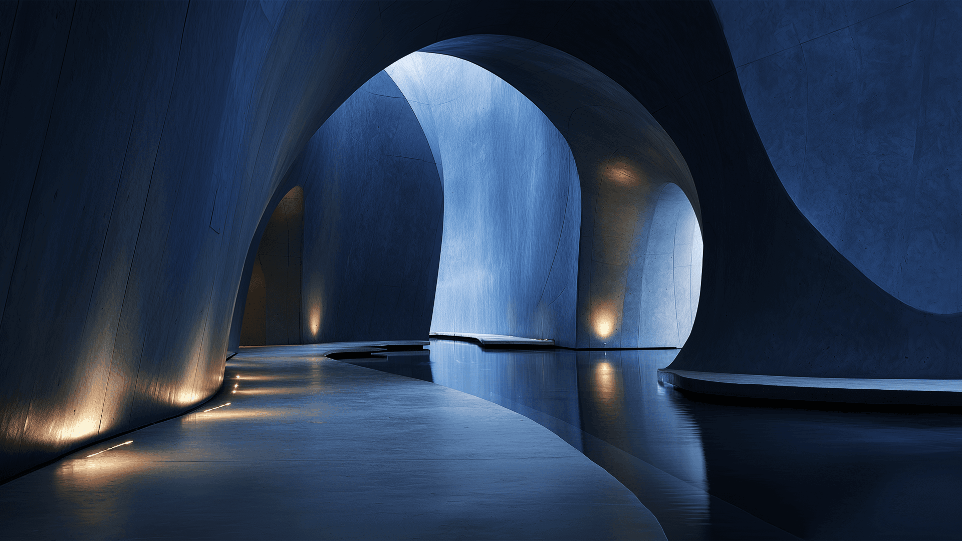 Interior arquitetônico futurista com grandes paredes curvas de concreto que formam arcos orgânicos. A iluminação geral é azulada e dramática, contrastando com luzes quentes embutidas no piso e nas paredes. Um espelho d'água sereno corre pelo centro do espaço, refletindo as formas curvas e a luz.