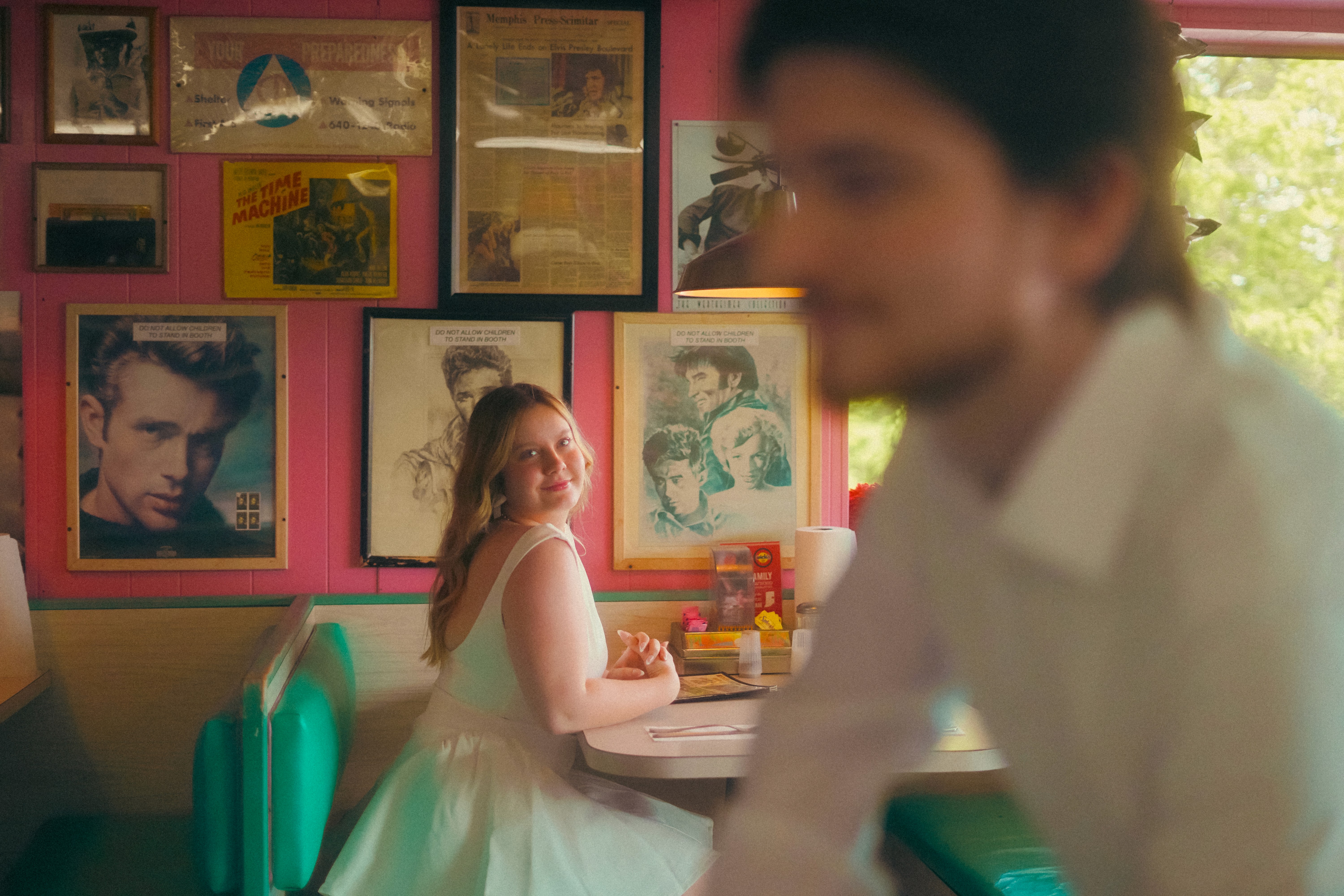A joyful couple stands back-to-back outdoors.