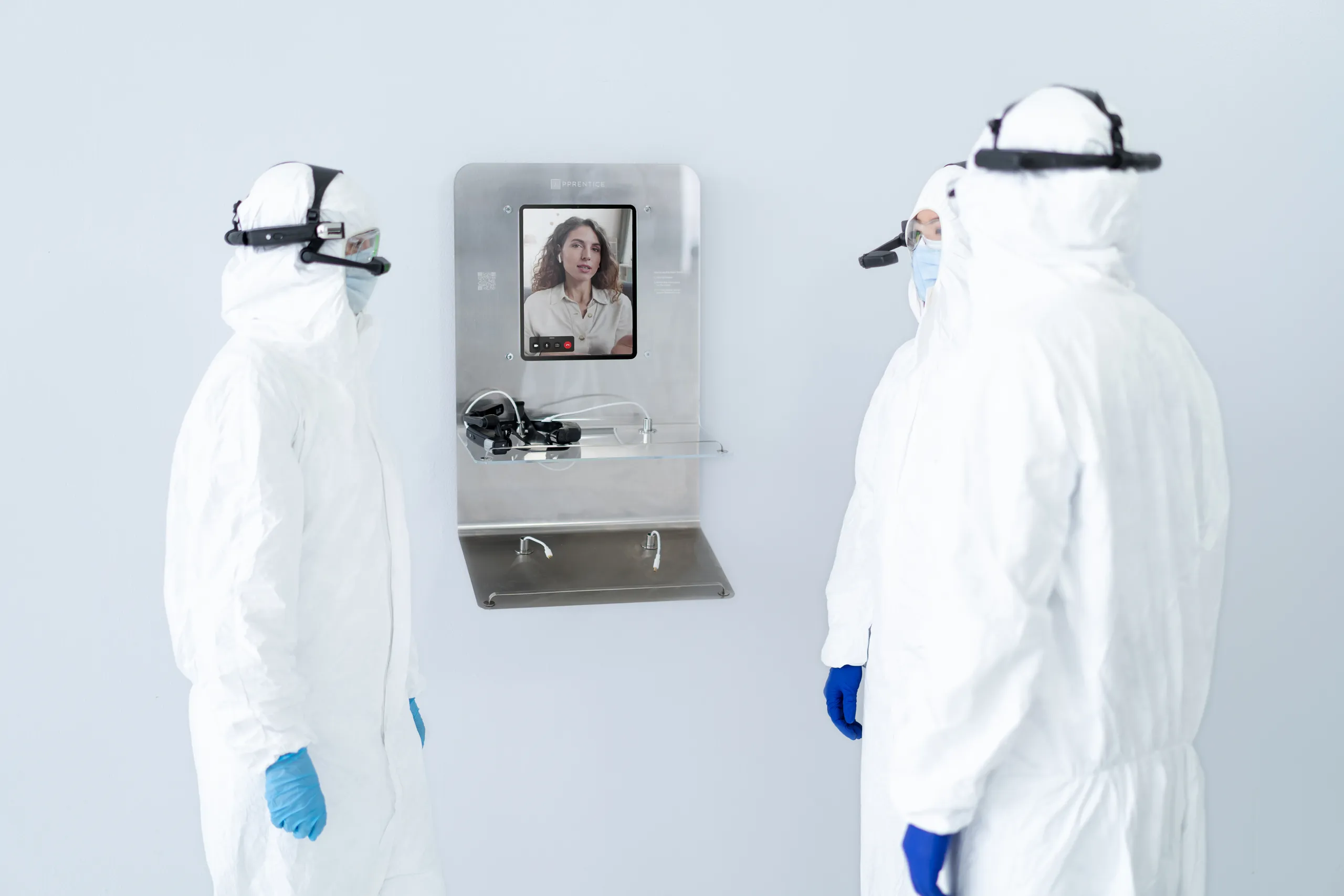 Three pharmaceutical lab workers in protective clothing using the Apprentice Tandem Hub for a remote video call