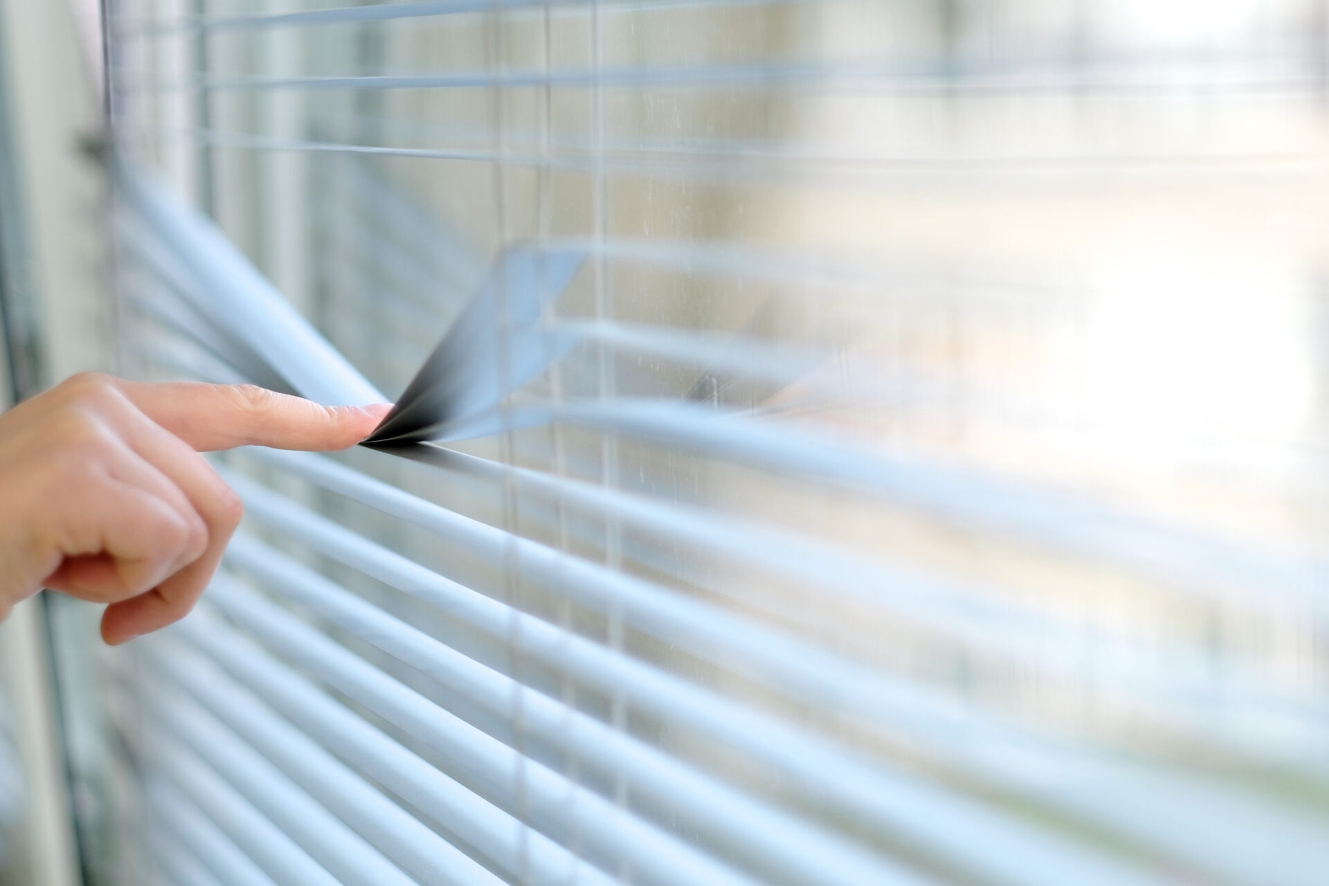 Index finger pressing on aluminum blinds. Wholesale Blind Factory