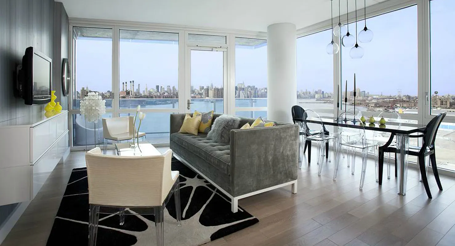A modern apartment interior showcasing a panoramic view of the city skyline through large windows.