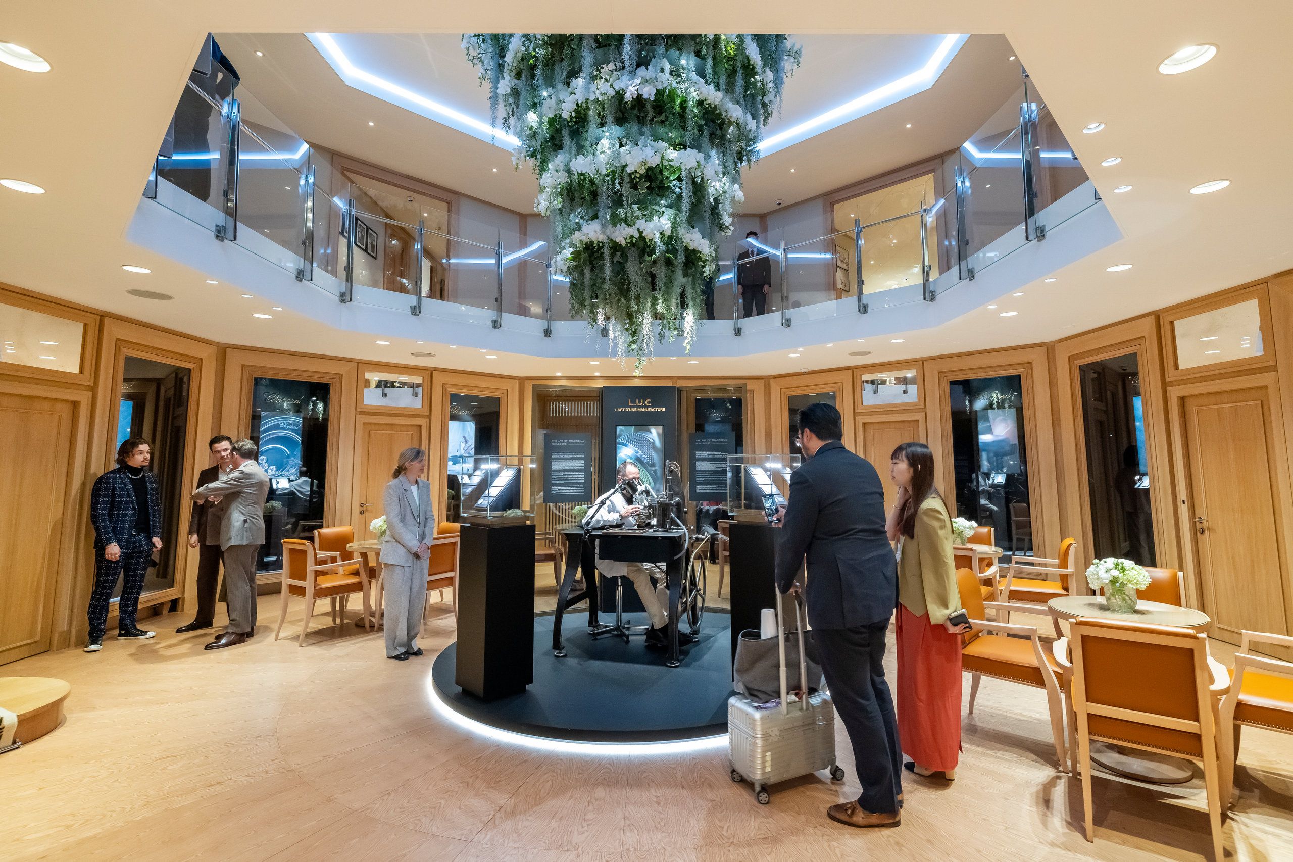 Chopard booth with cascading floral ceiling installation and elegant watch display area