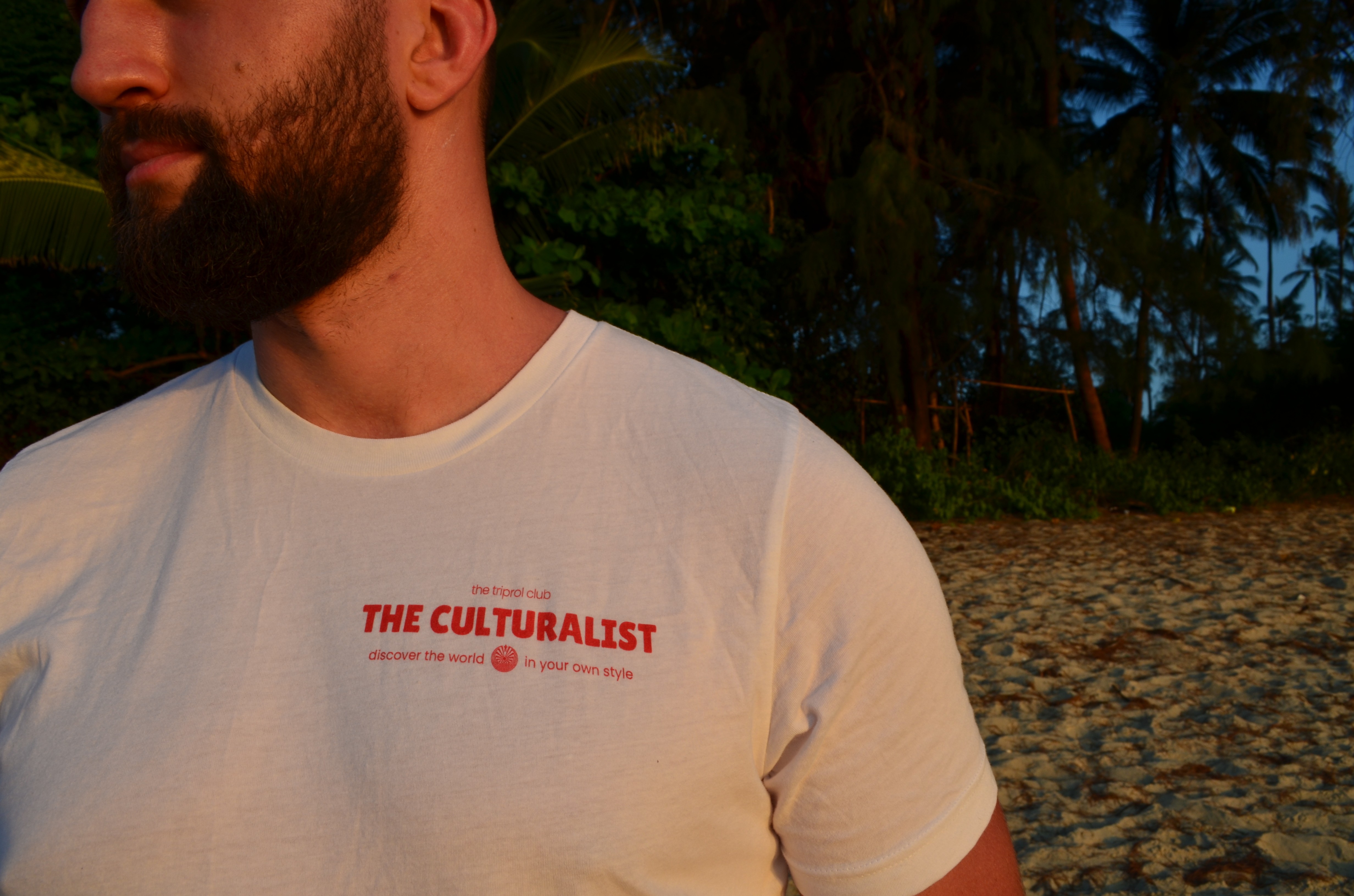 Smiling young woman with long hair standing against a dark green background, holding a finger to her chin.