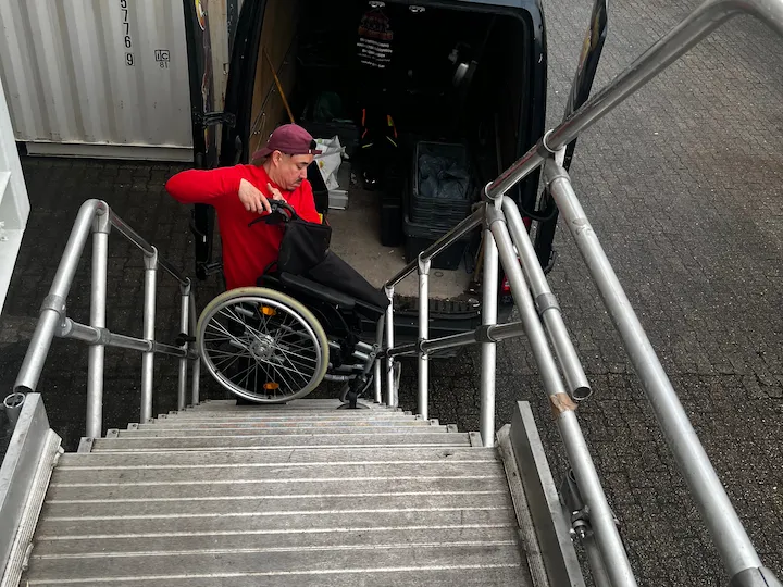 Mitarbeiter lädt einen Rollstuhl aus dem Transporter an der Lagerfläche