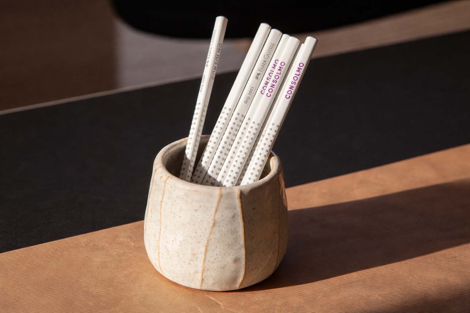 Branding-Detail mit Bleistiften inklusive logo in keramischem Becher auf Tisch