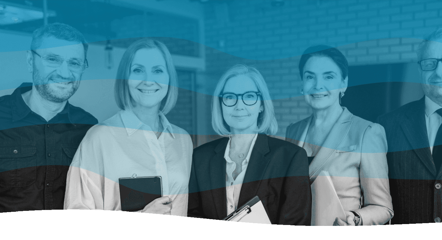 A group of five diverse professionals, dressed in formal attire, stand together in an office setting, with some holding clipboards, suggesting a collaborative business environment.