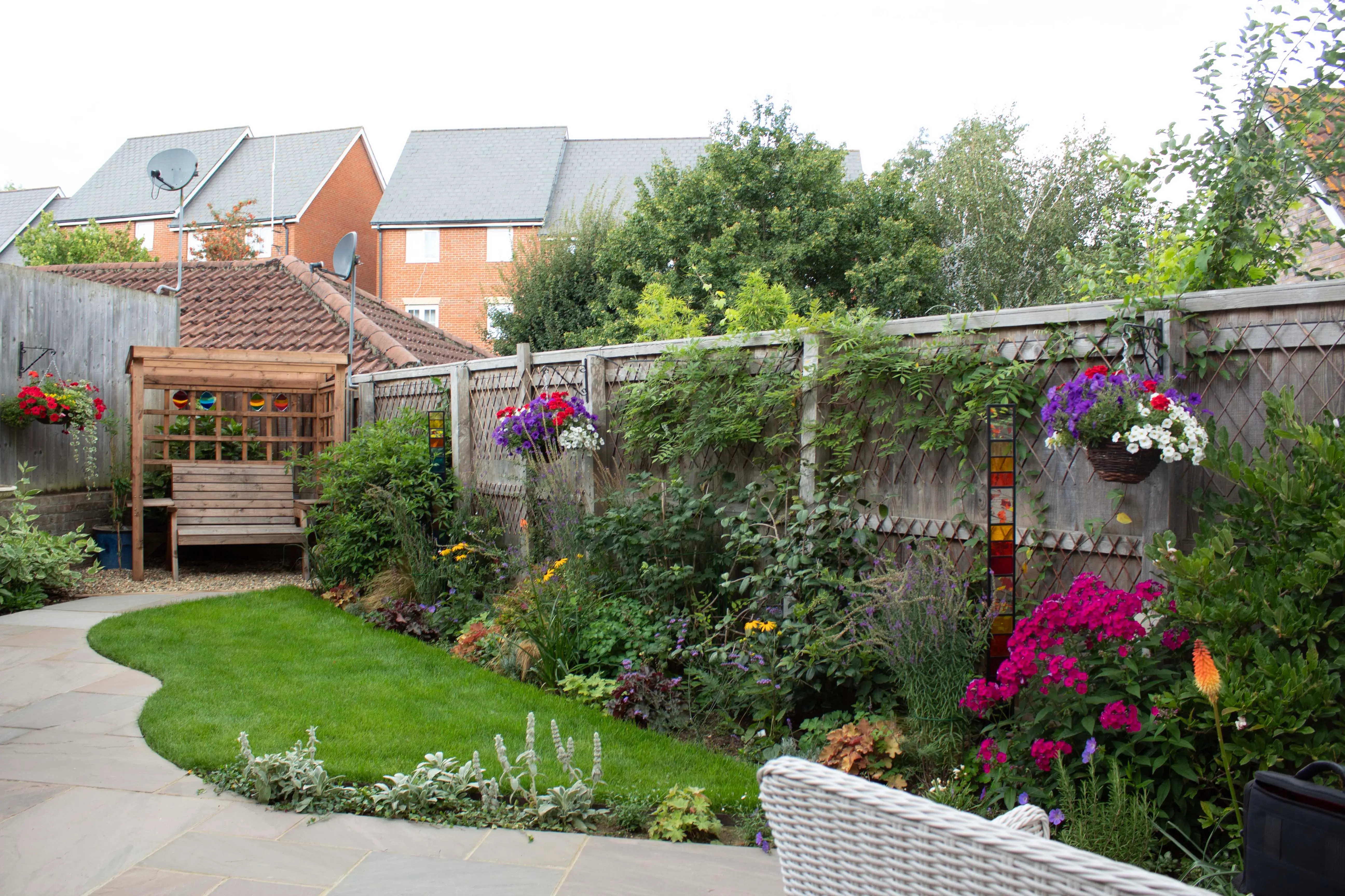 A vibrant garden featuring lush greenery, colorful flowers, and a serene path leading to a shaded area.