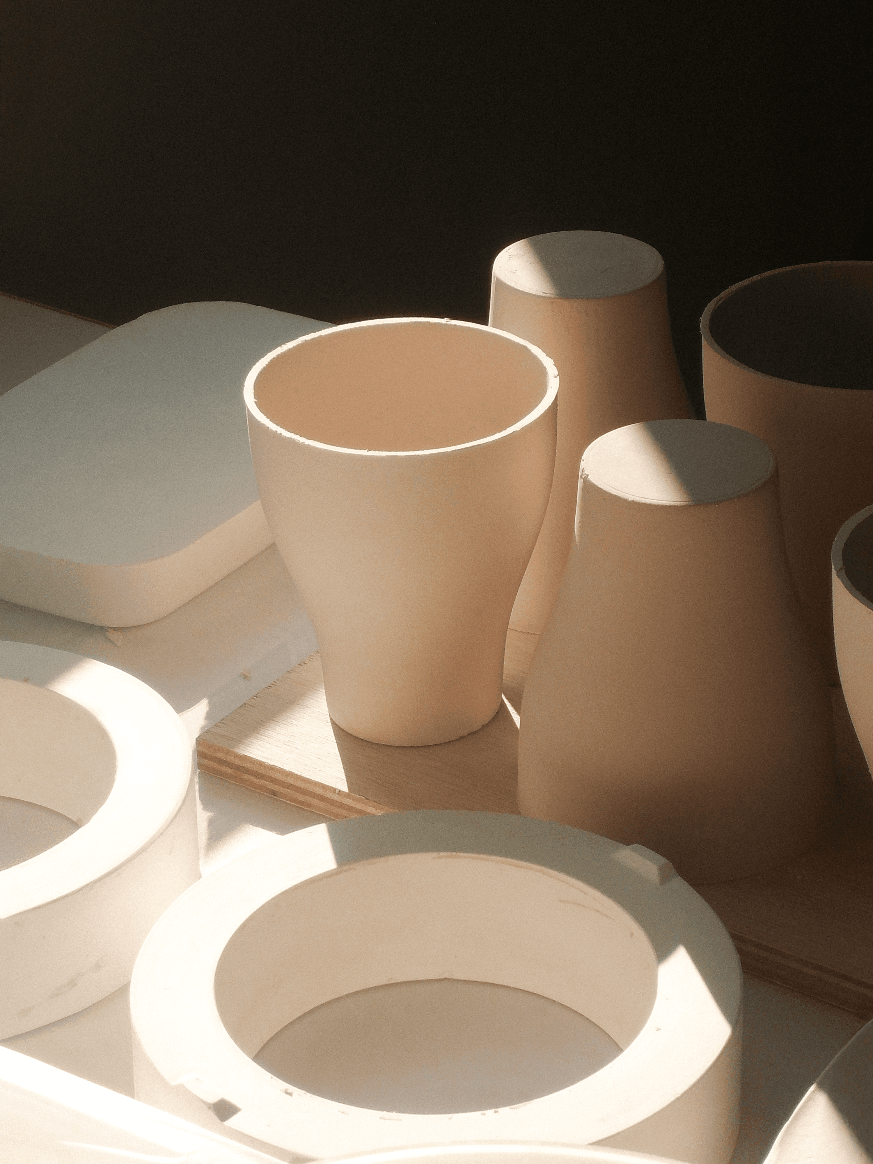 Person wearing a beige apron whisking green matcha tea in a ceramic bowl on a kitchen counter.