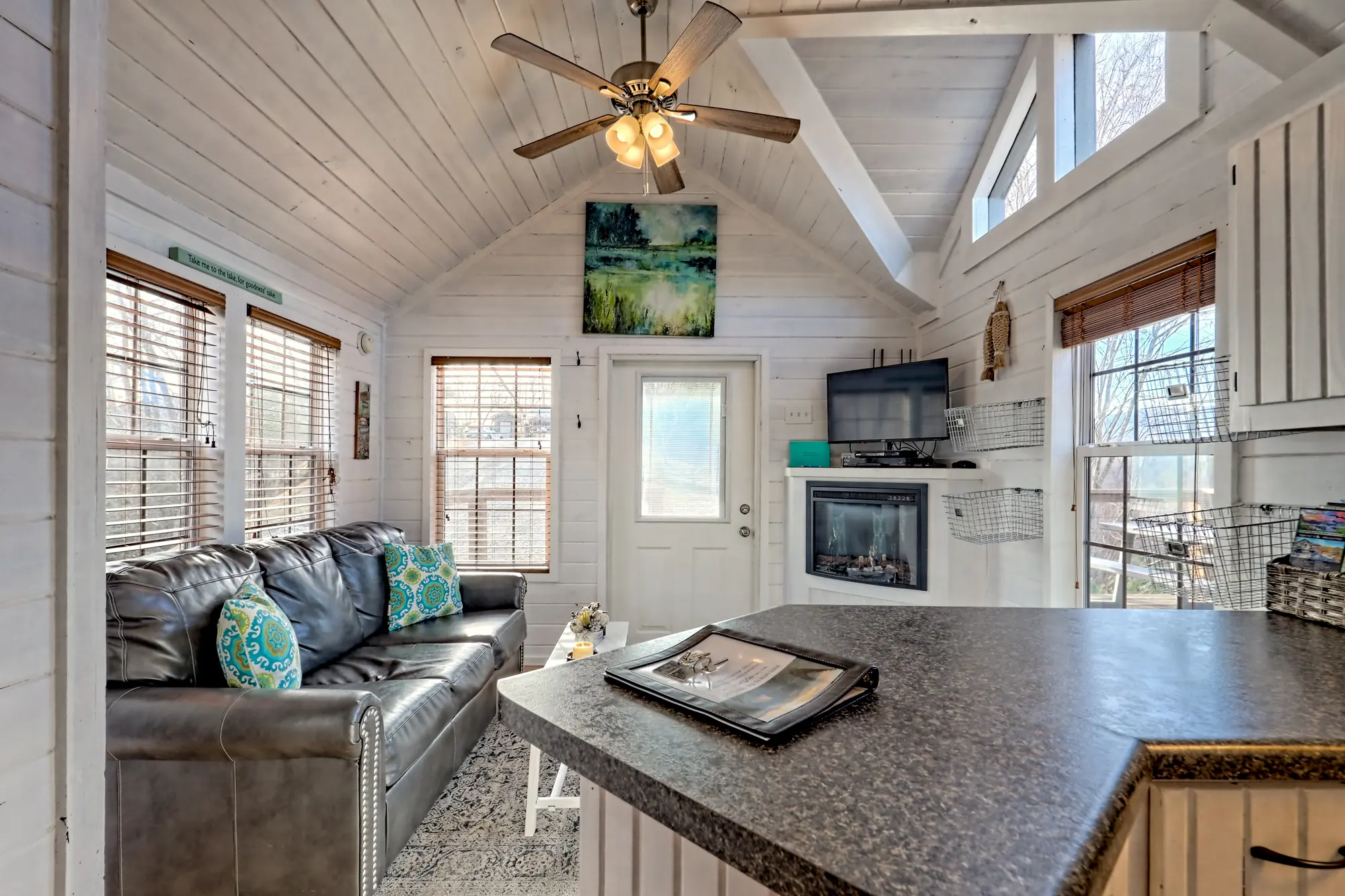 Tiny Tuck living area with an electric fireplace, TV and ceiling fan