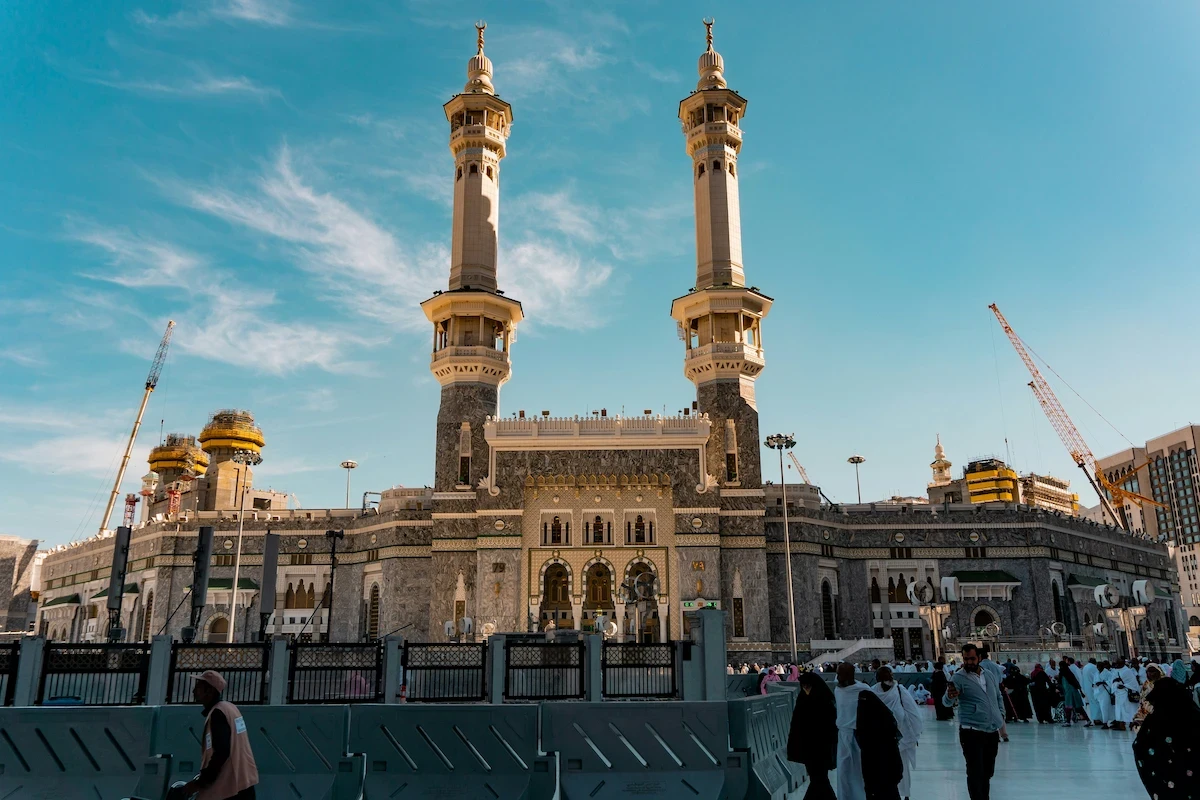 Exterior view of Masjid al-Haram in Mecca, Saudi Arabia, featuring mosque minarets and courtyard.