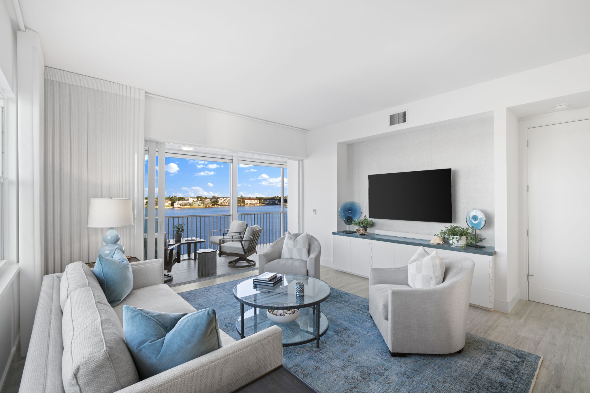a white living room with blue accents on the furniture and a mounted flatscreen TV in the background