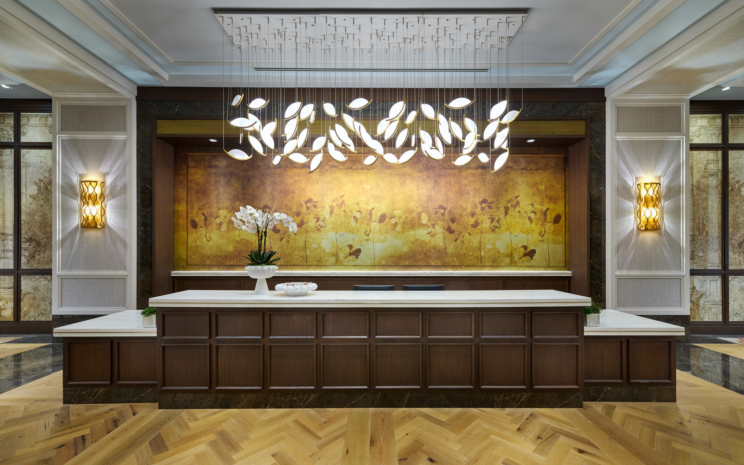 Hotel lobby reception desk, ornate chandelier and artwork.