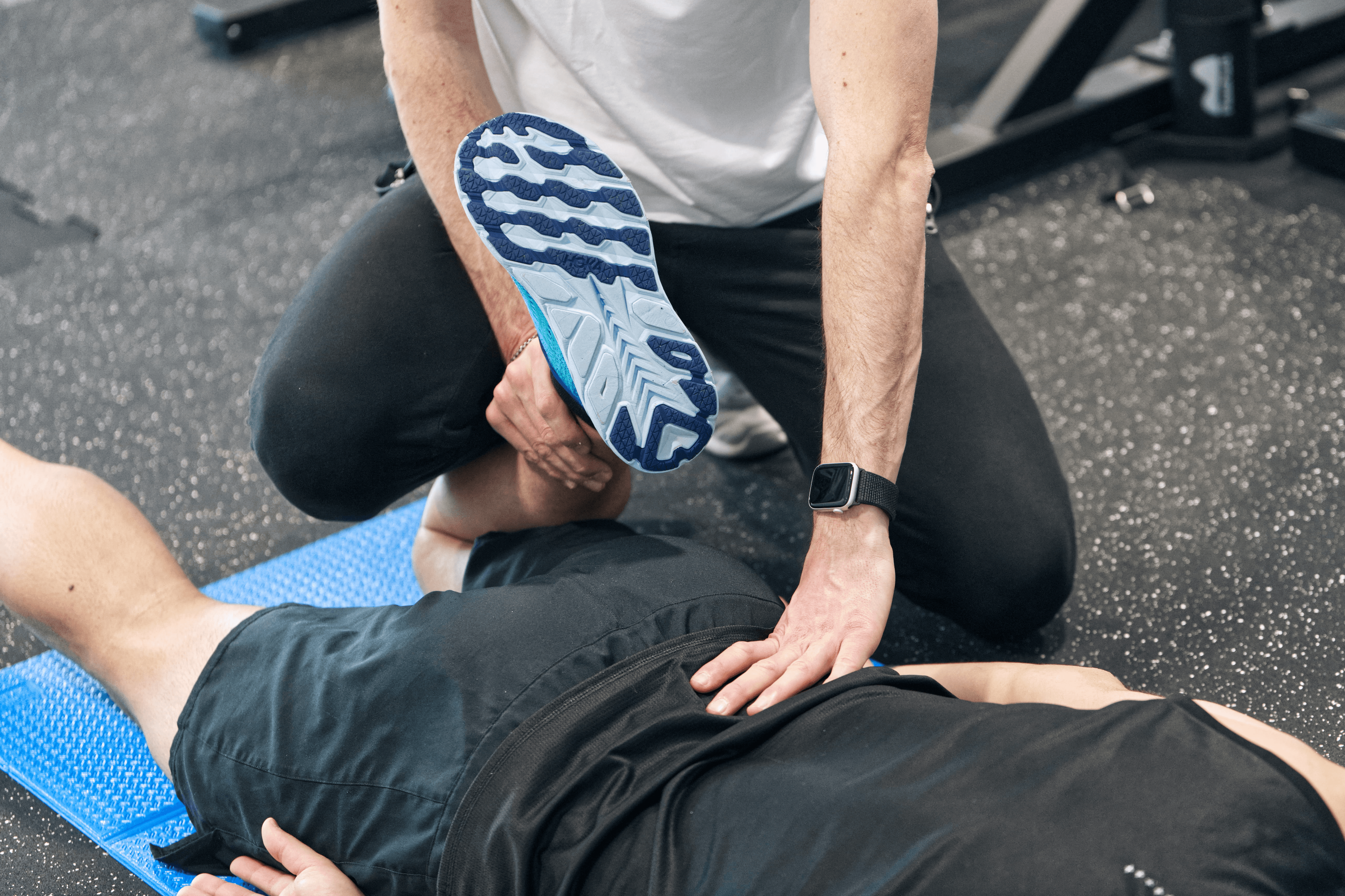 A person with glasses and a beard smiles warmly while working on a laptop at a desk. The setting is casual and relaxed, with a neutral background