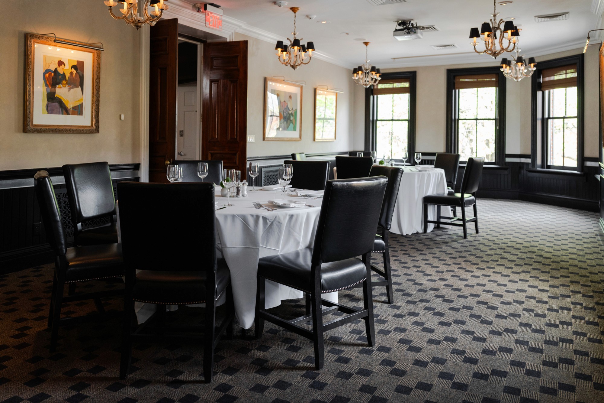 Mohawk Room at Lindey's with round tables, leather chairs, chandeliers and framed art