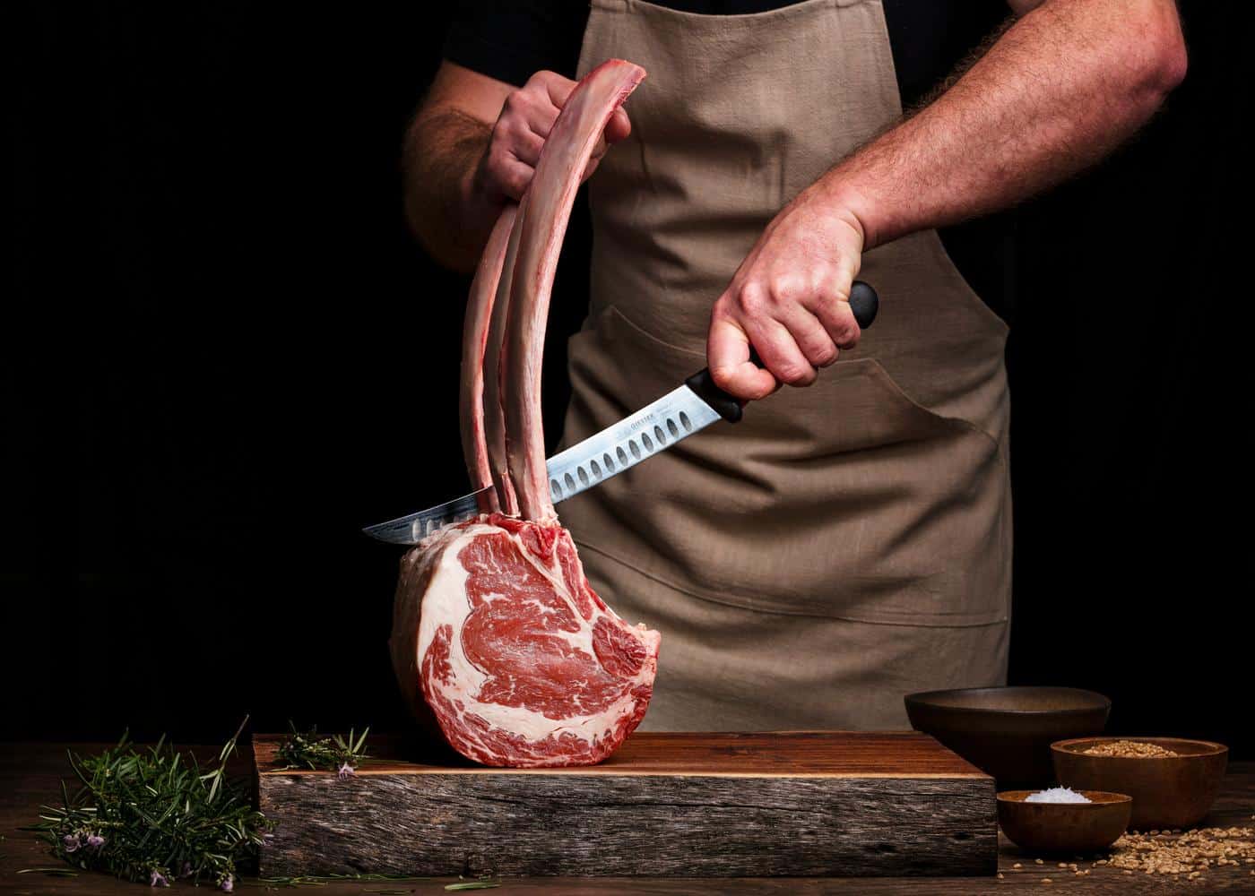 Man using big knife to cut into a piece of raw meat for carnivore diet