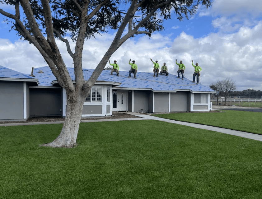 Roofs 4 Less roofing crew waving from a completed roof replacement project in the Central Valley