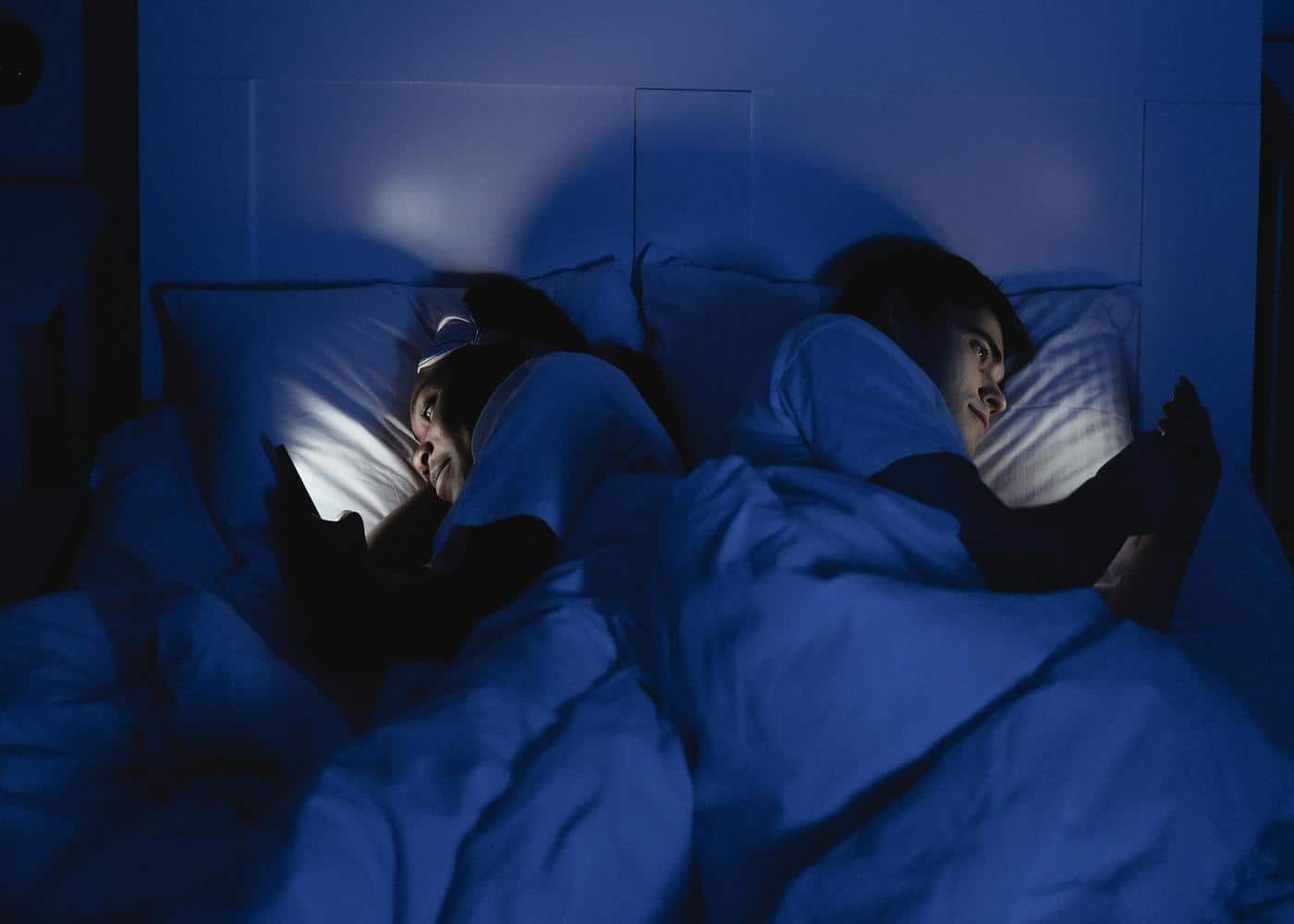 Sleep architecture hacks: Two people looking at their phones in bed