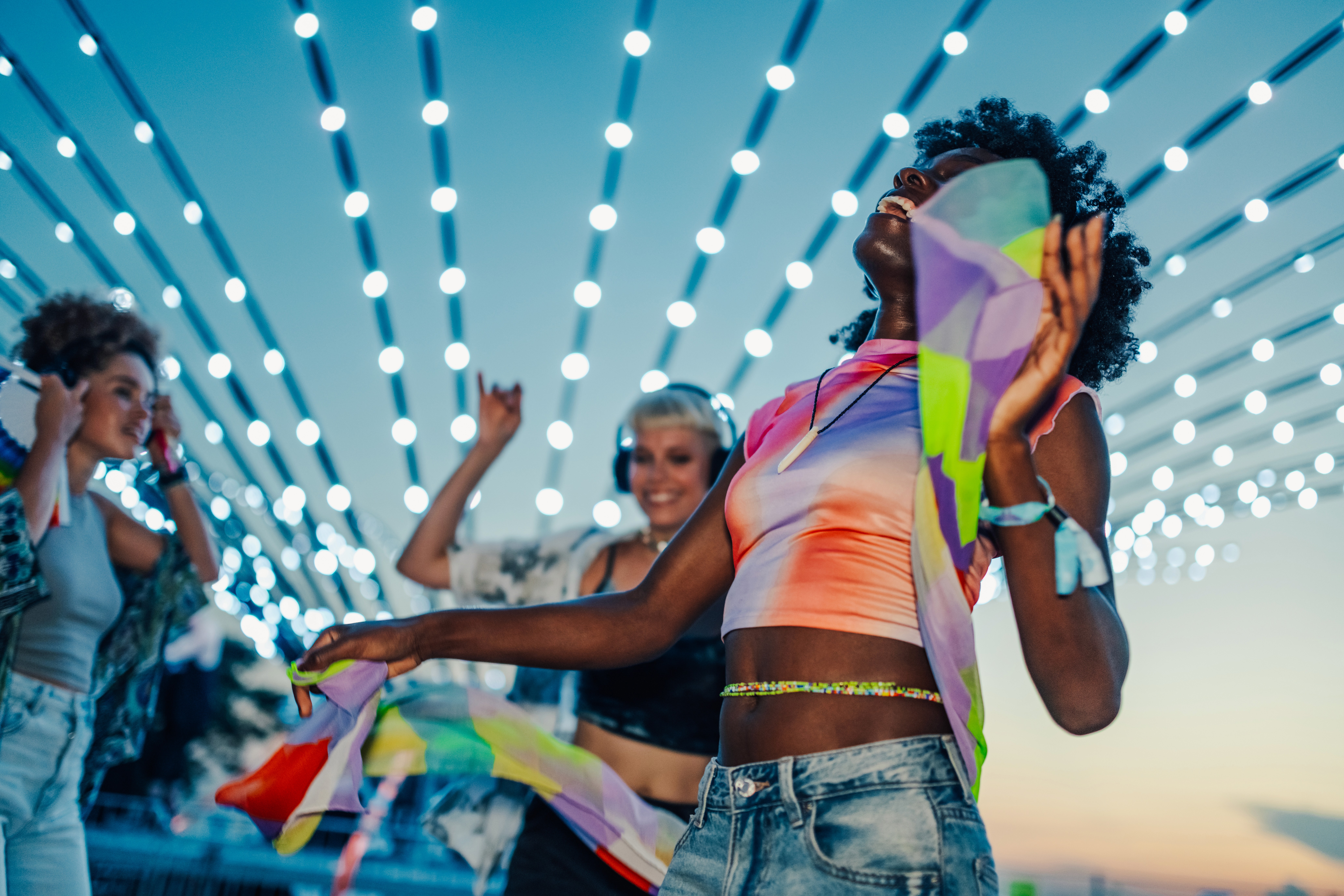 A group of people at a music festival dancing during dusk.