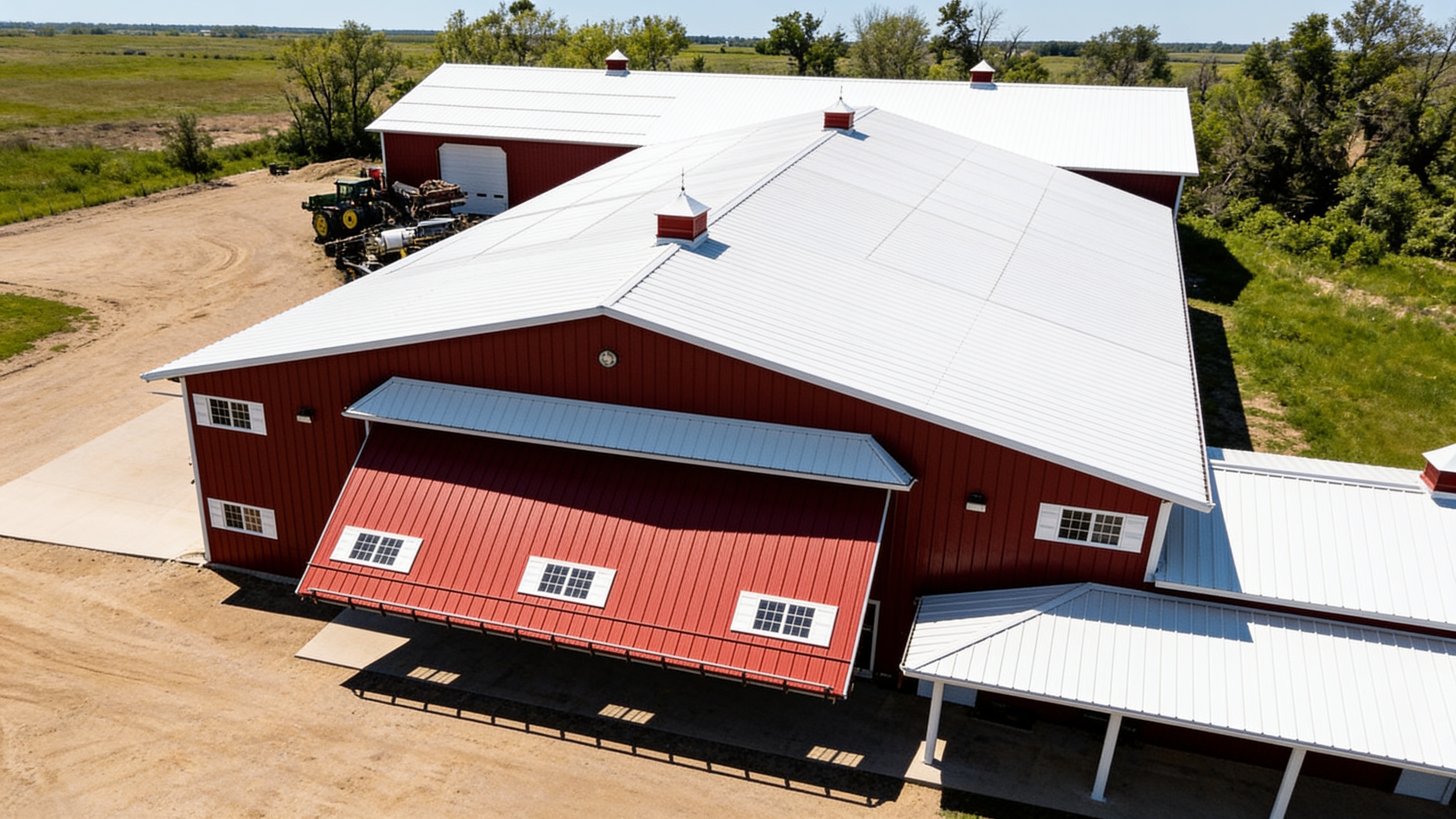 Aerial view of a red metal shop with an open hydraulic agricultural
