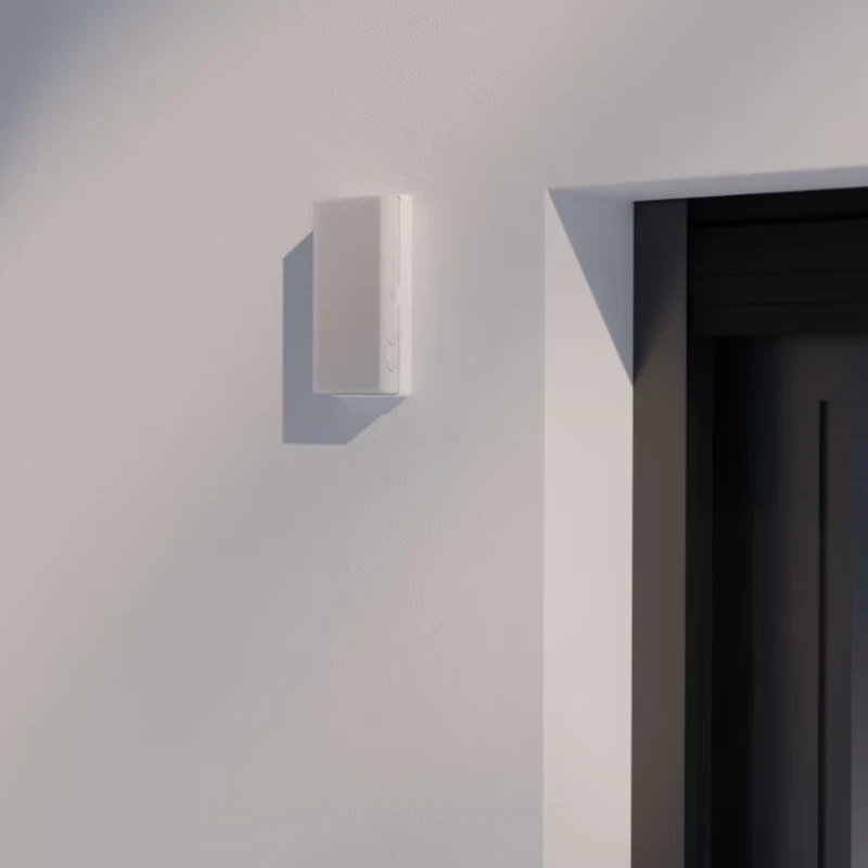 Weißer Funkschalter an einer hellen Hauswand neben einer dunklen Tür