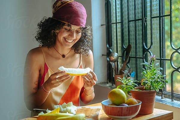 woman in white dress holding silver fork and knife slicing green vegetable on white ceramic bowl