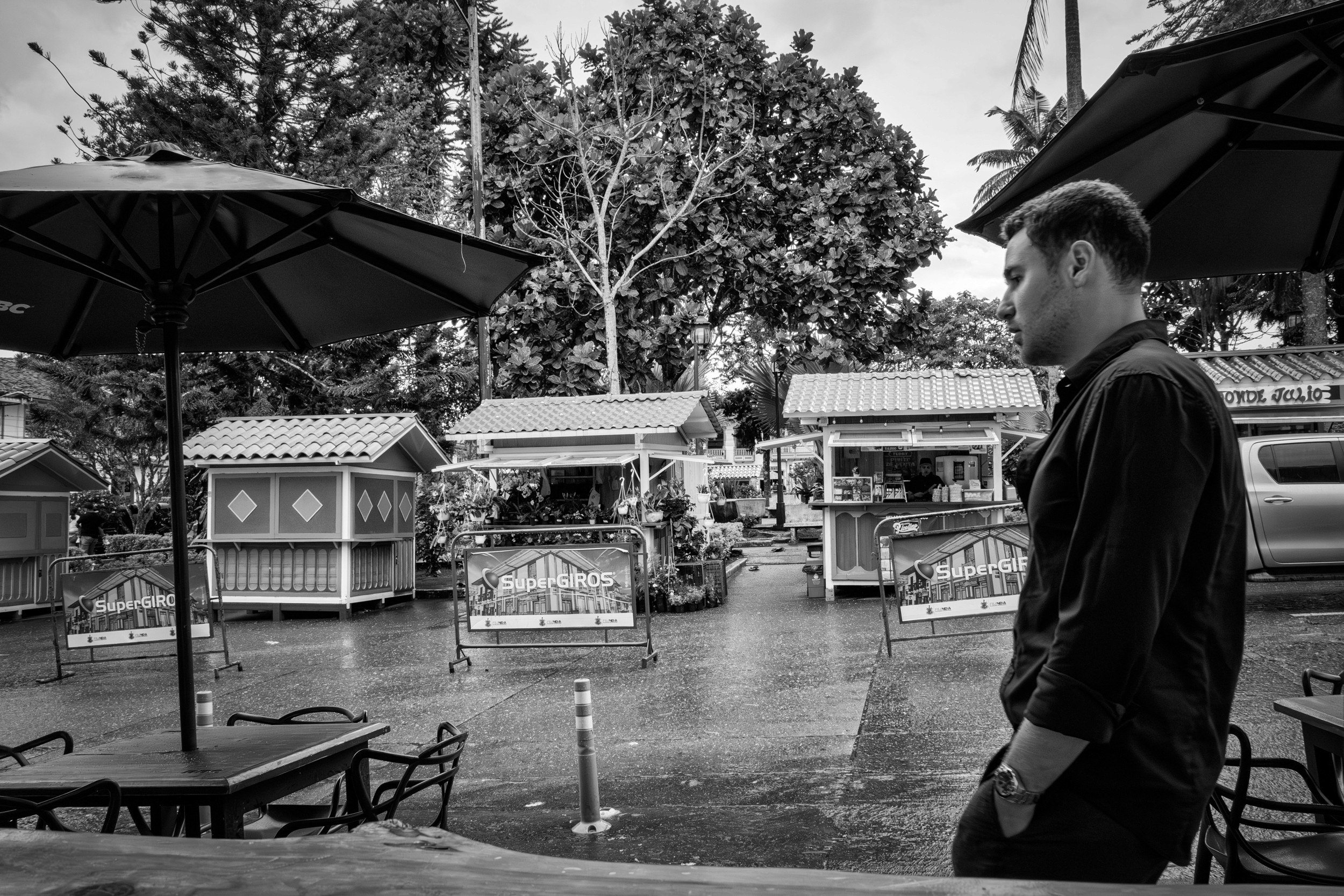 Rainy street scene with people passing by a bar window.
