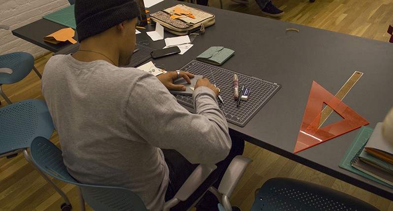 A man sitting at a workshop desk and working on something.