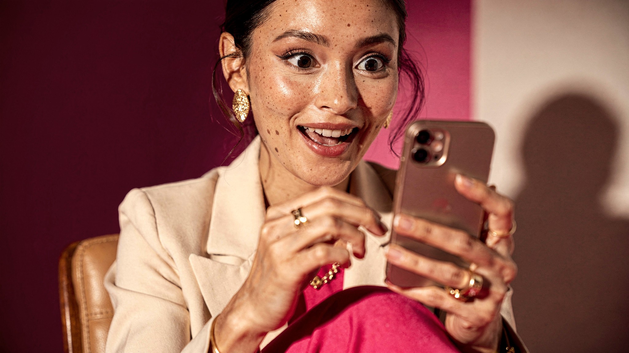 Adult woman creator scrolling her phone with a surprised, delighted expression