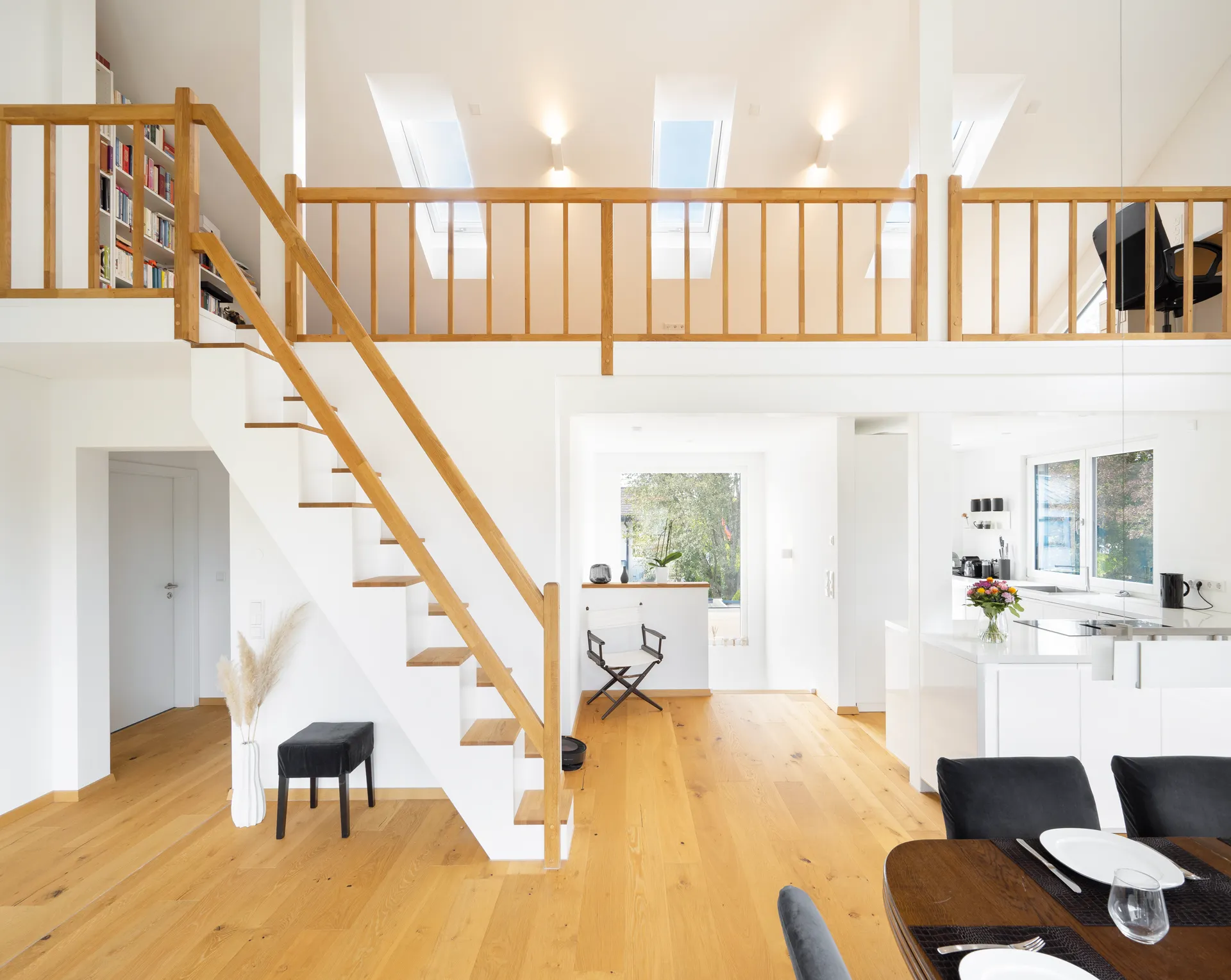 Helles, modernes Wohnhaus mit Holztreppe, Bücherregal, Dachfenstern, Einbauküche und Essbereich.