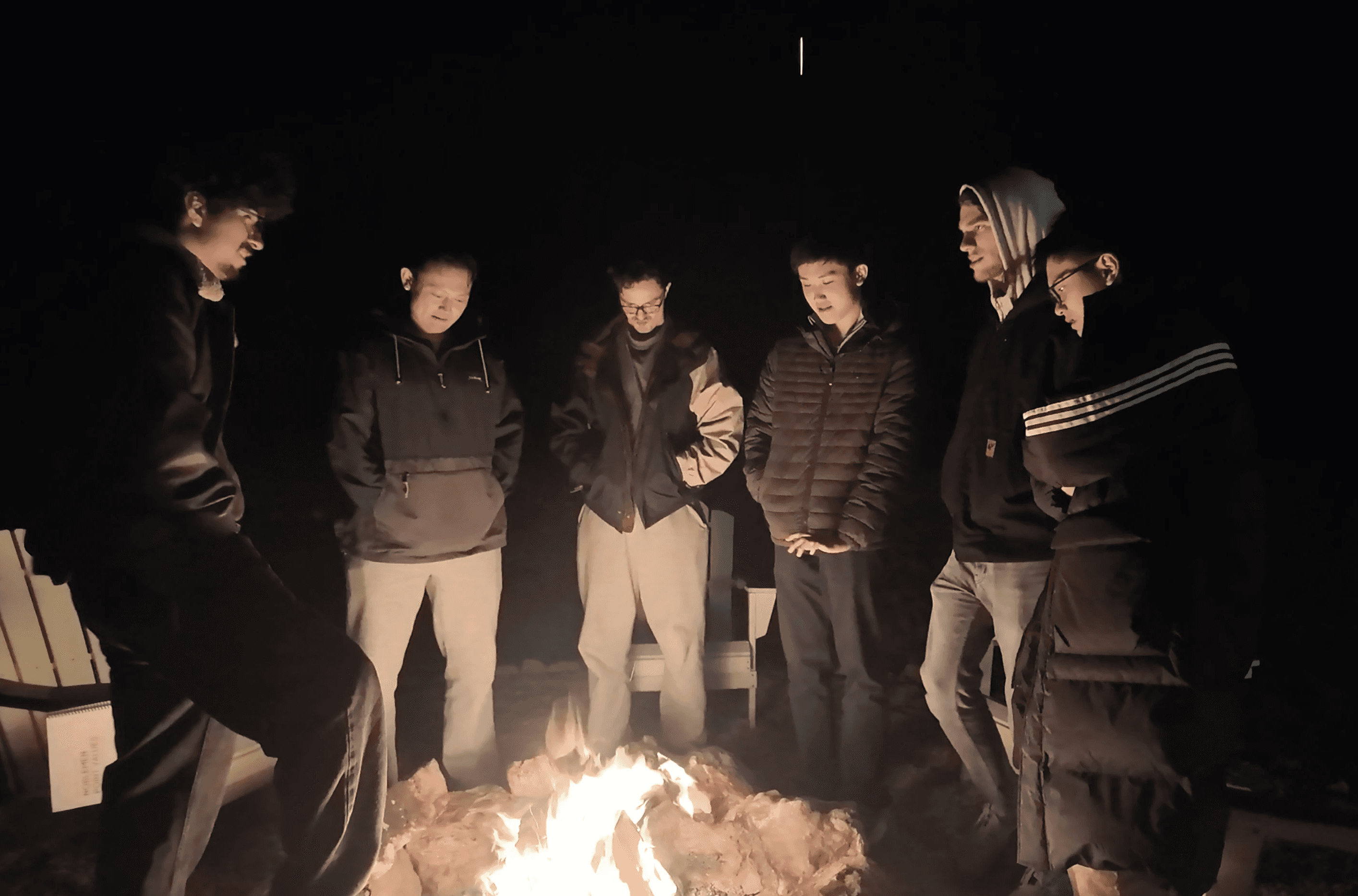 Guys hanging out around campfire