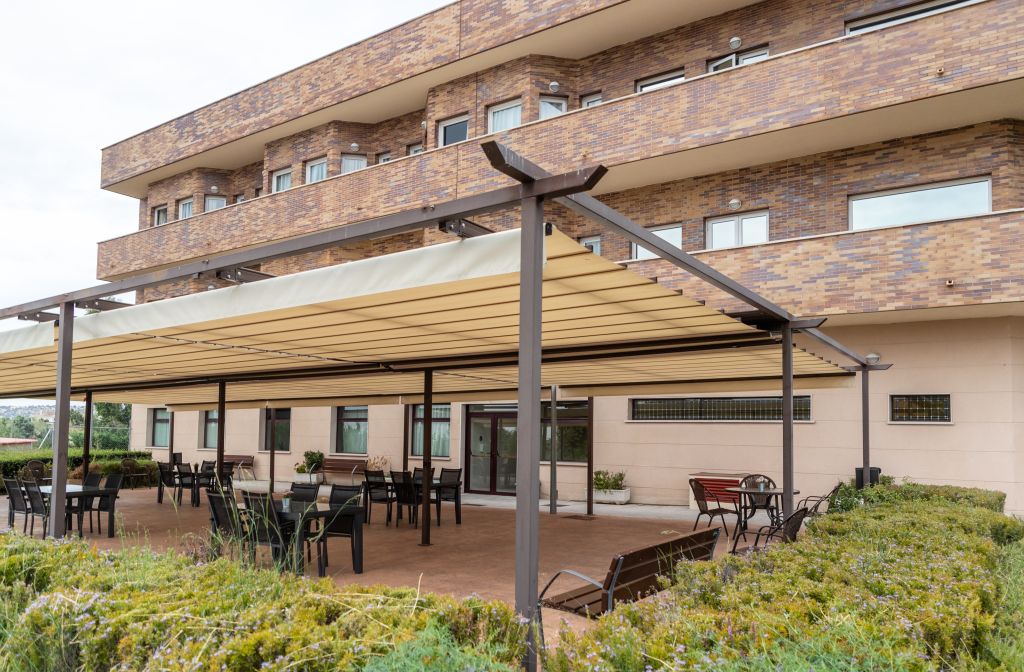 Outdoor seating area with retractable shade canopy and garden landscaping.