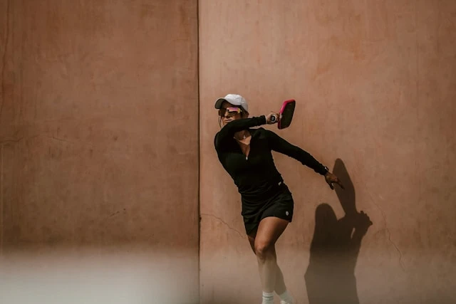 Person walking on a treadmill in a gym with large windows and city light