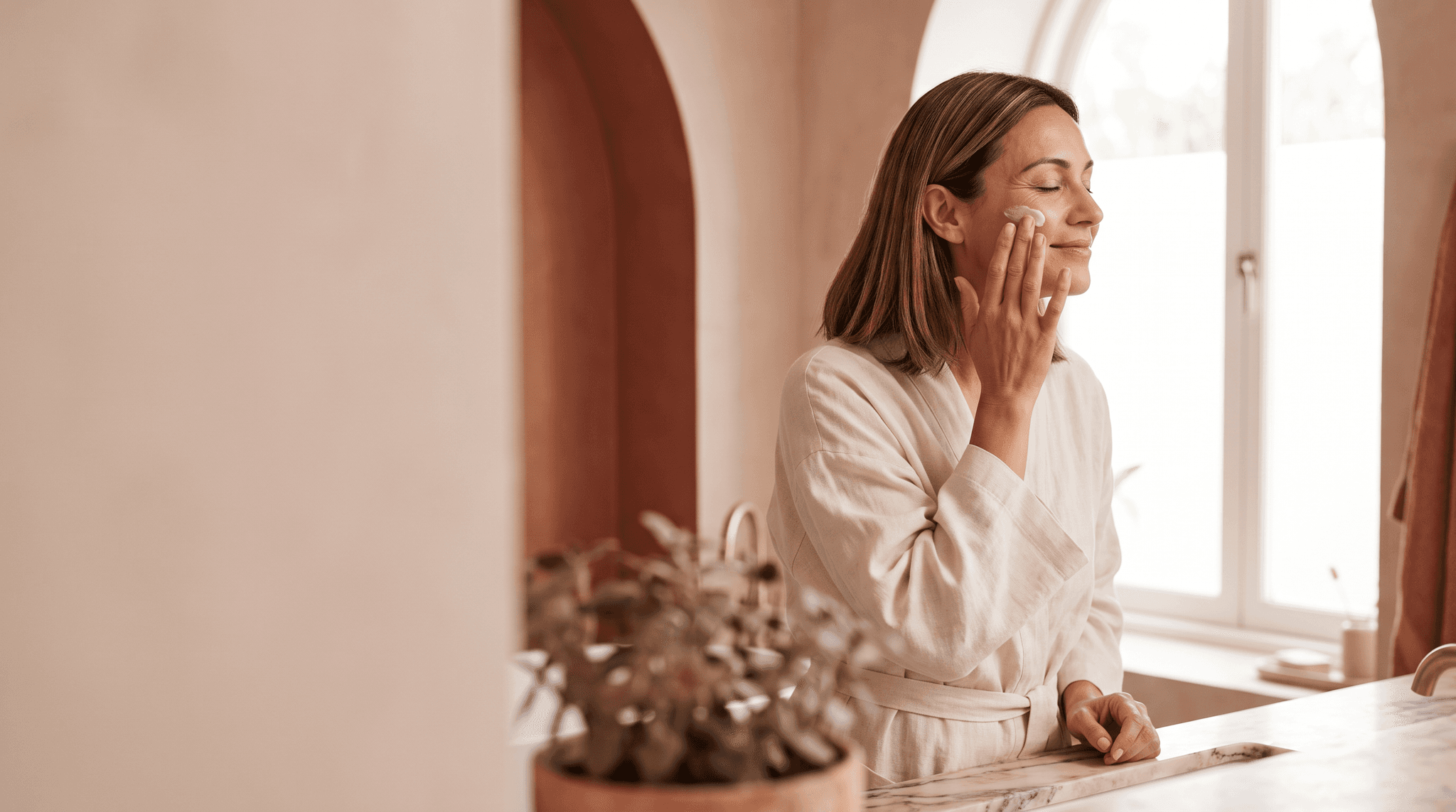 Frau trägt am Morgen eine Pflegecreme auf ihre Wange auf (KI-generiert)