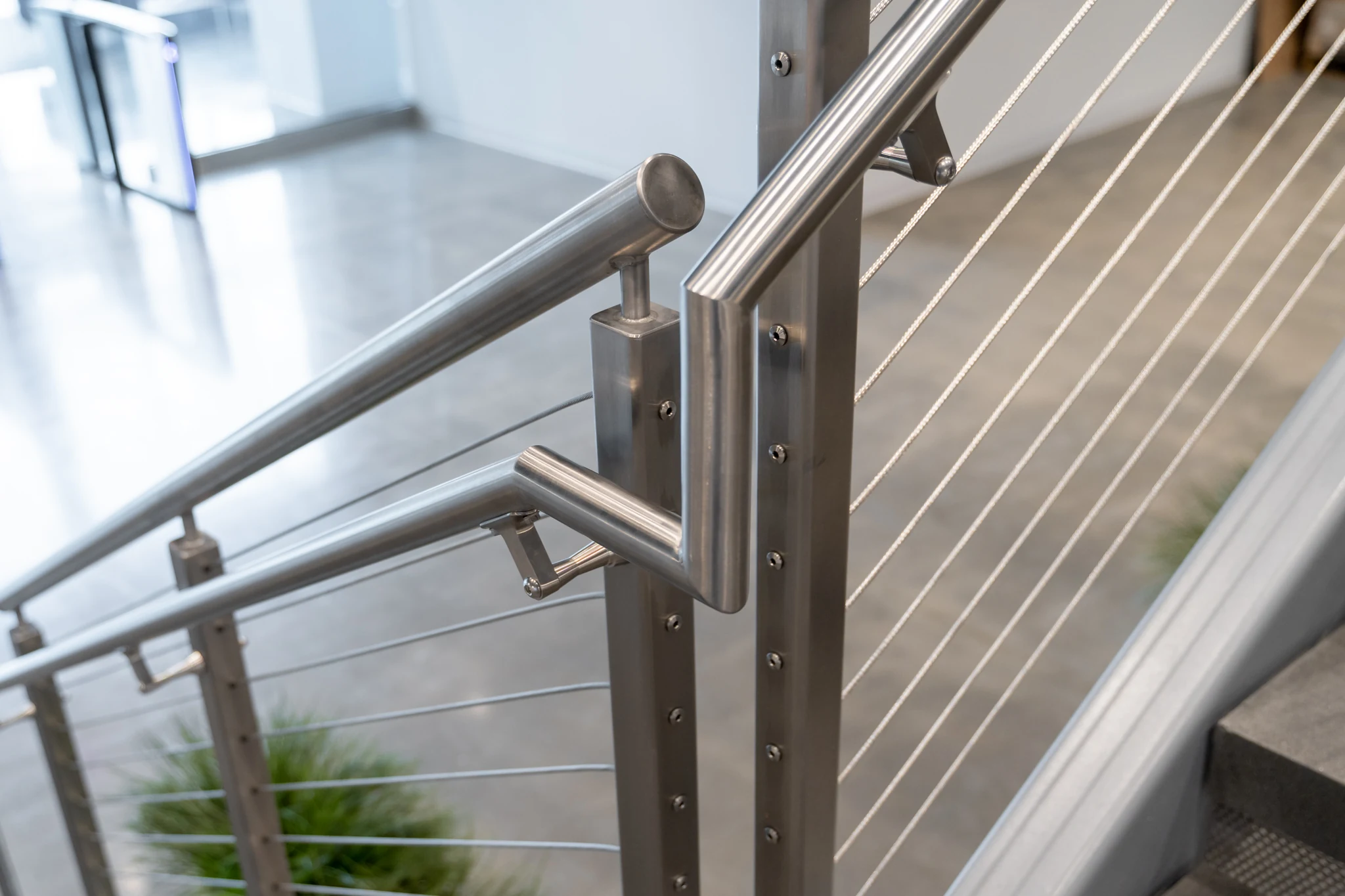 Detail of metal handrail brackets and cable railing beside the stairs at TQL