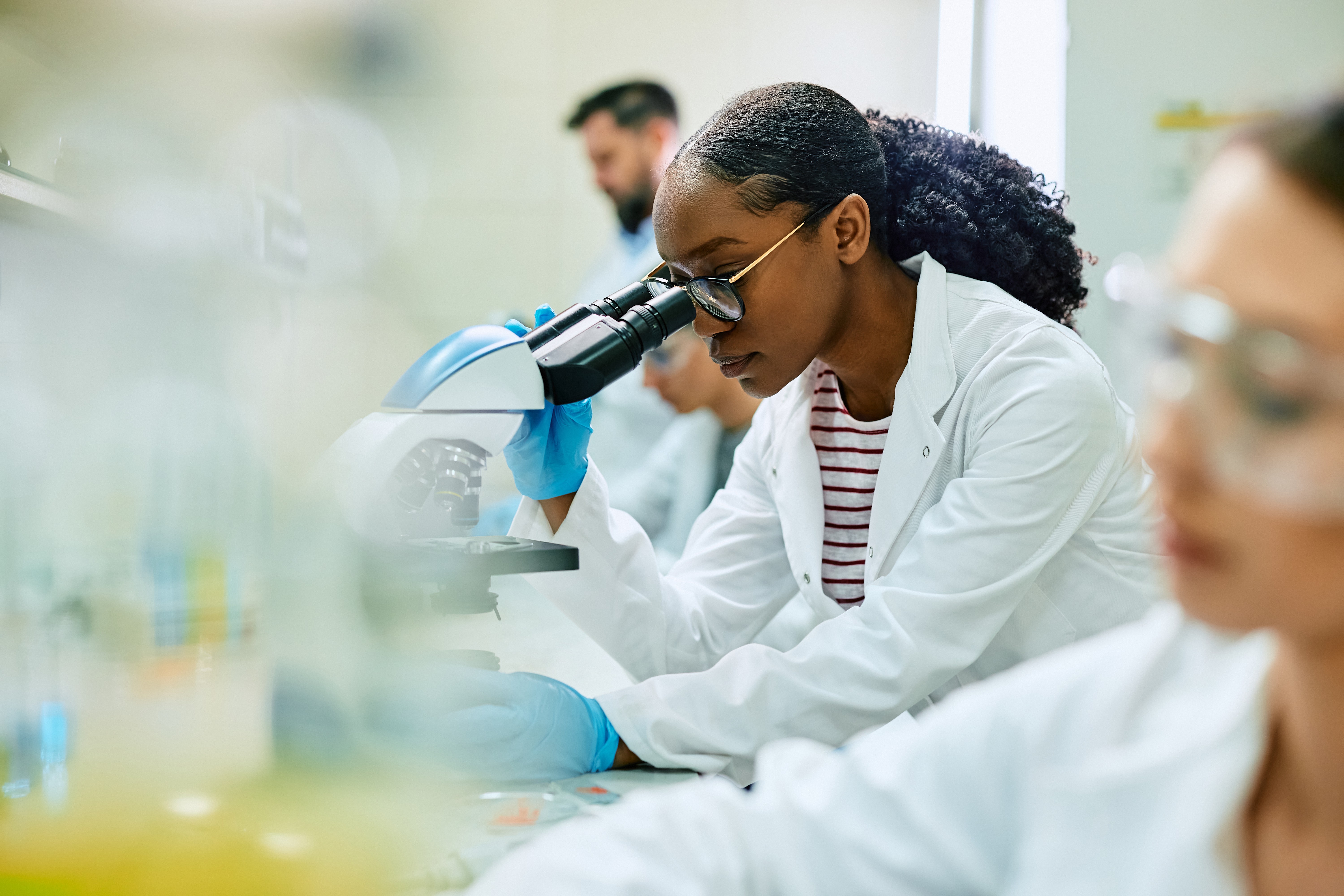 Female scientist working in a laboratory, looking through a microscope.