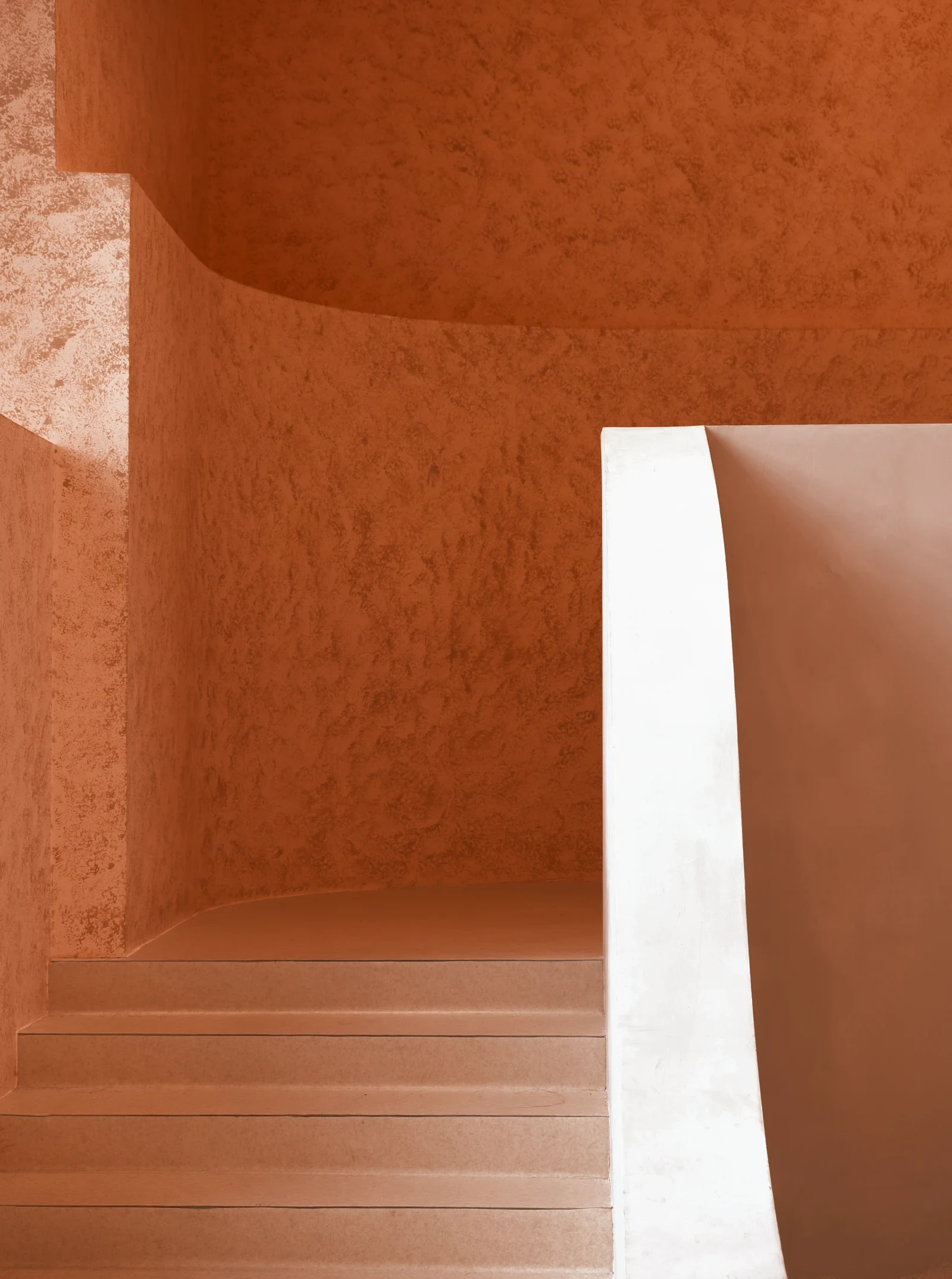 A curved white stair against an orange wall