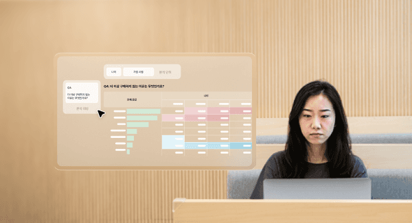 A woman sitting at a desk with a laptop, displaying data visuals on a screen in a modern workspace.