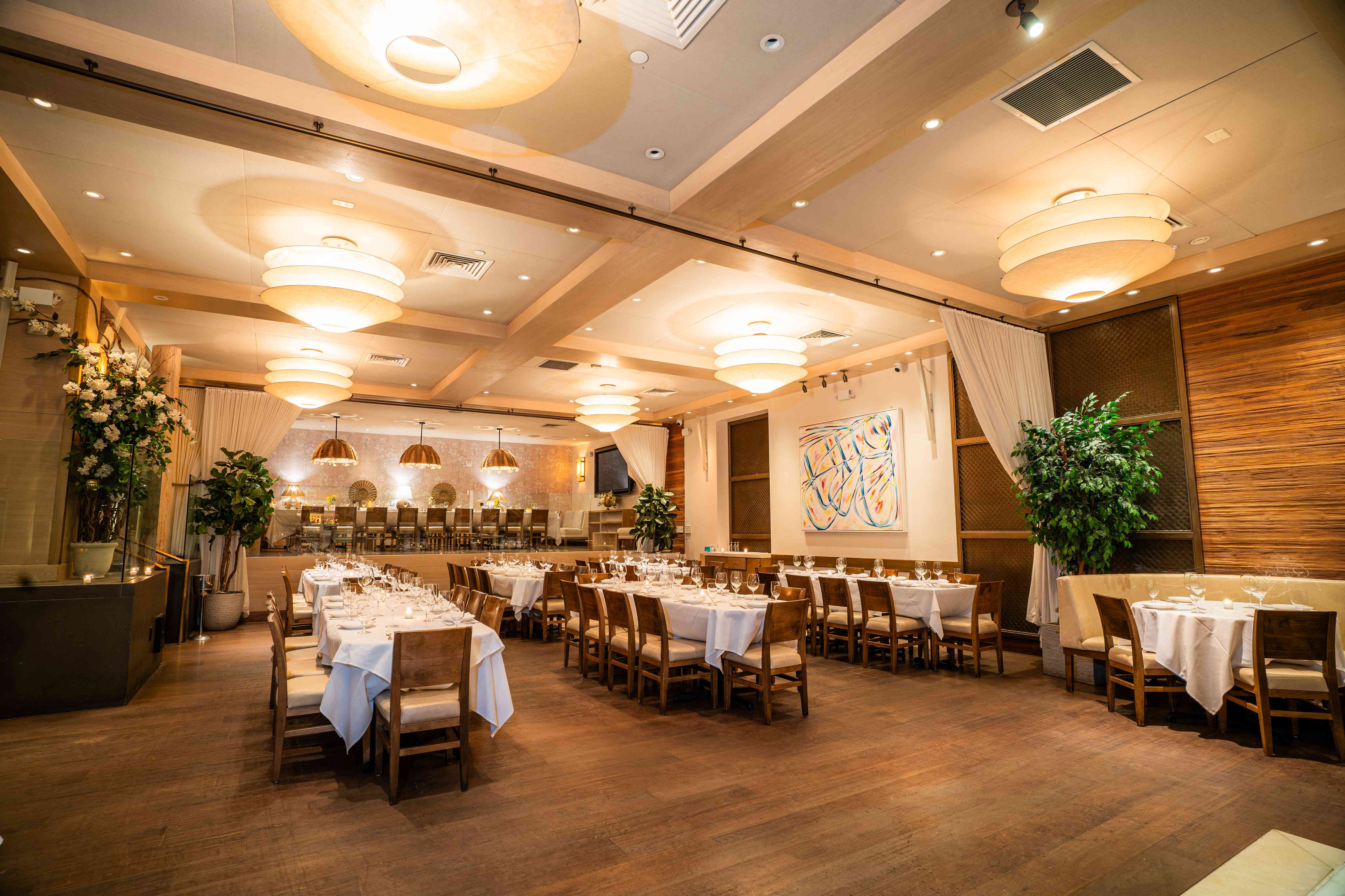 Elegant restaurant interior featuring tables set for dining, soft lighting, and decorative plants.