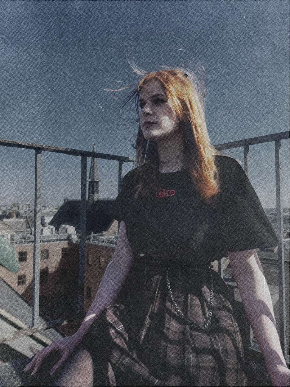 streetwear model wearing black t-shirt with red creep word mark in urban city enviroment.